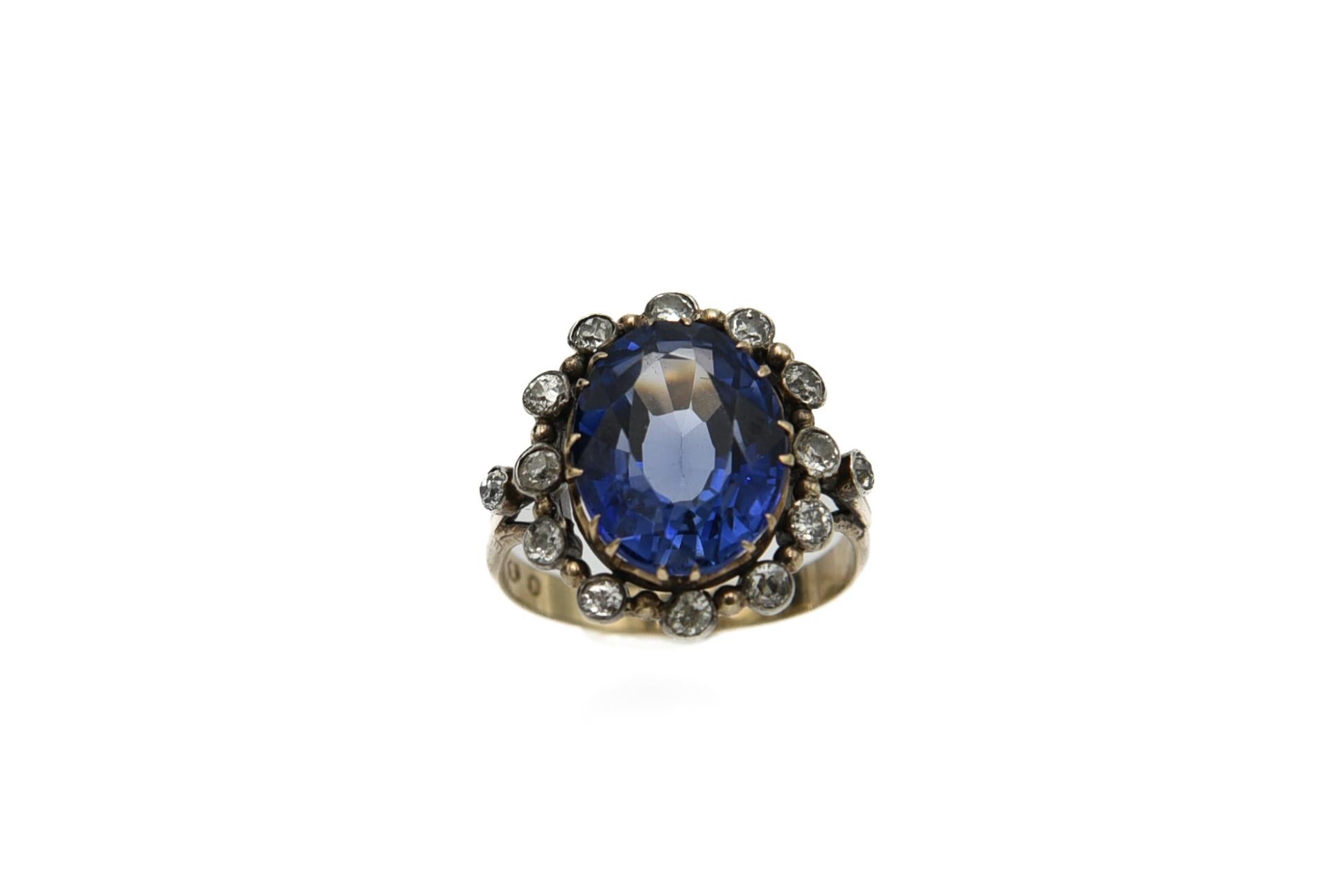 Ein altpolnischer Ring mit einem mittig gefassten großen synthetischen Saphir von schöner tiefblauer Farbe und 14 seitlichen Diamanten im 