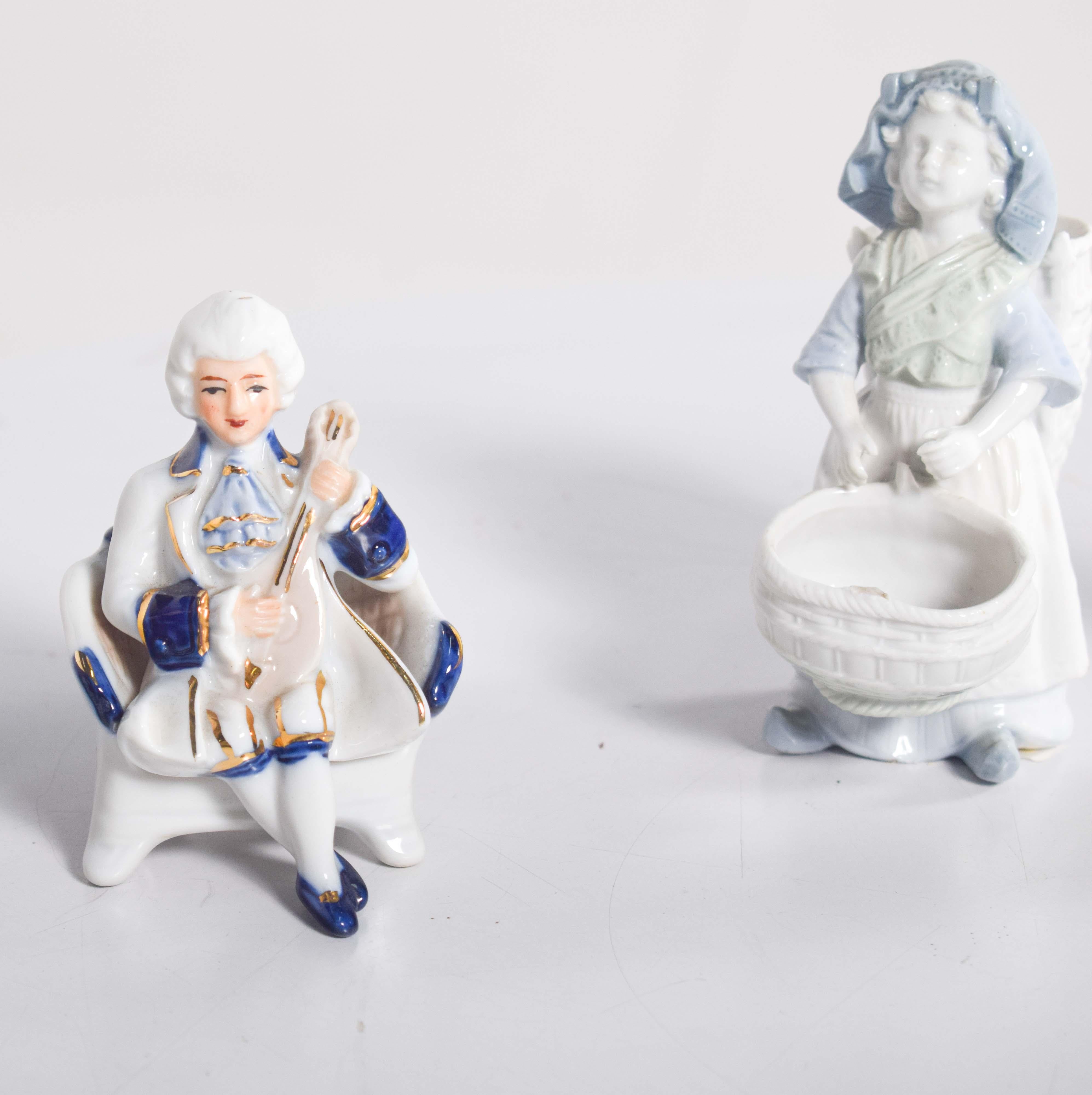 This charming collection of four porcelain figures presents a variety of decorative styles and motifs, blending musical and pastoral themes. Two of the figures depict a young boy playing the mandolin, dressed in outfits adorned with elegant white,