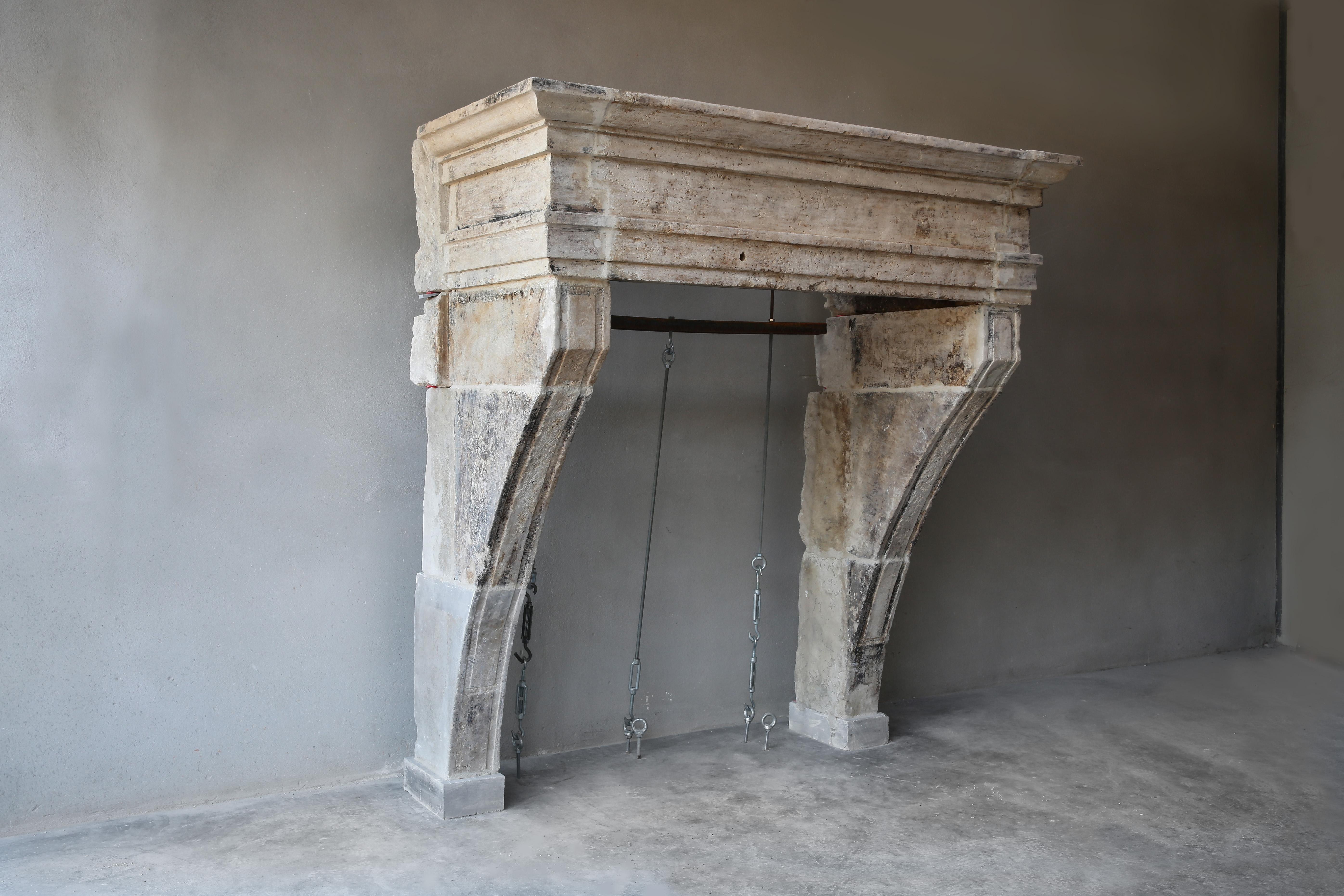 A very robust and beautiful antique fireplace from the 19th century! This French limestone fireplace in Campagnarde style contains beautiful lines and ornaments on the slightly curved legs. The front section is wide, which gives this chimney a lot