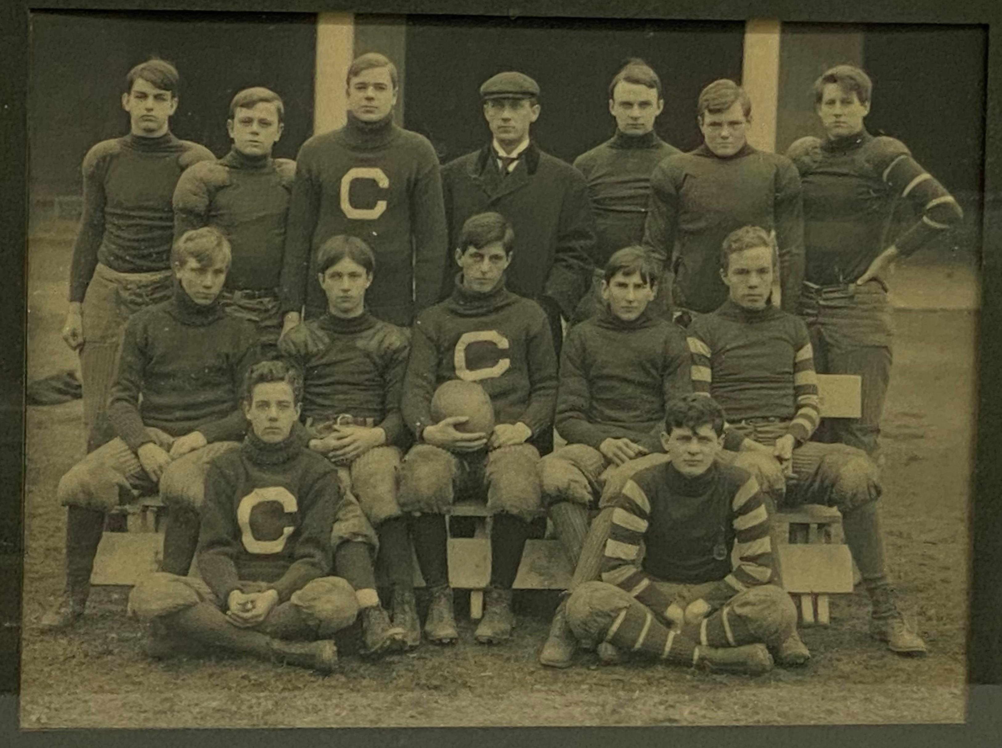 Fourteen man photo with coach or manager standing row center and thirteen football players. Smaller pads and way less protection than today's game. Circa 1907. The reverse is inscribed with players' names and possible projected year of graduation.