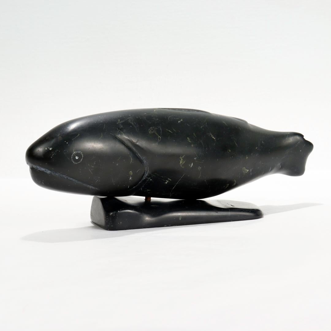 A fine carved stone sculpture.

In the form of a salmon or other fish.

In 2 parts. Comprised of salmon fish supported on a carved plinth joined by a central wooden dowel.

Signed Pov likely for Simon Pov.

With Inuit characters possibly for Port