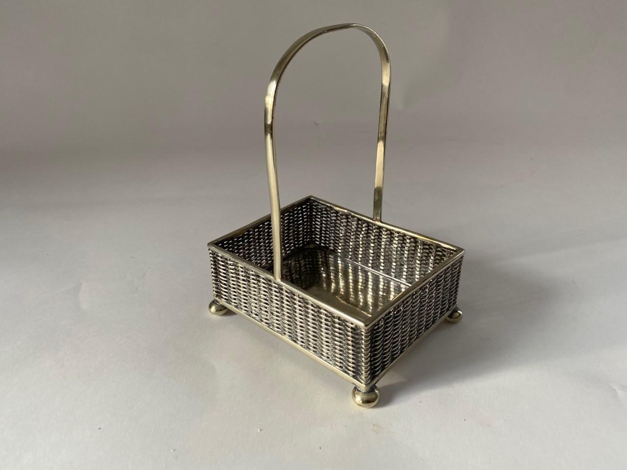 Attractive old small silver plate woven basket with tall loop handle and bun feet from England.
