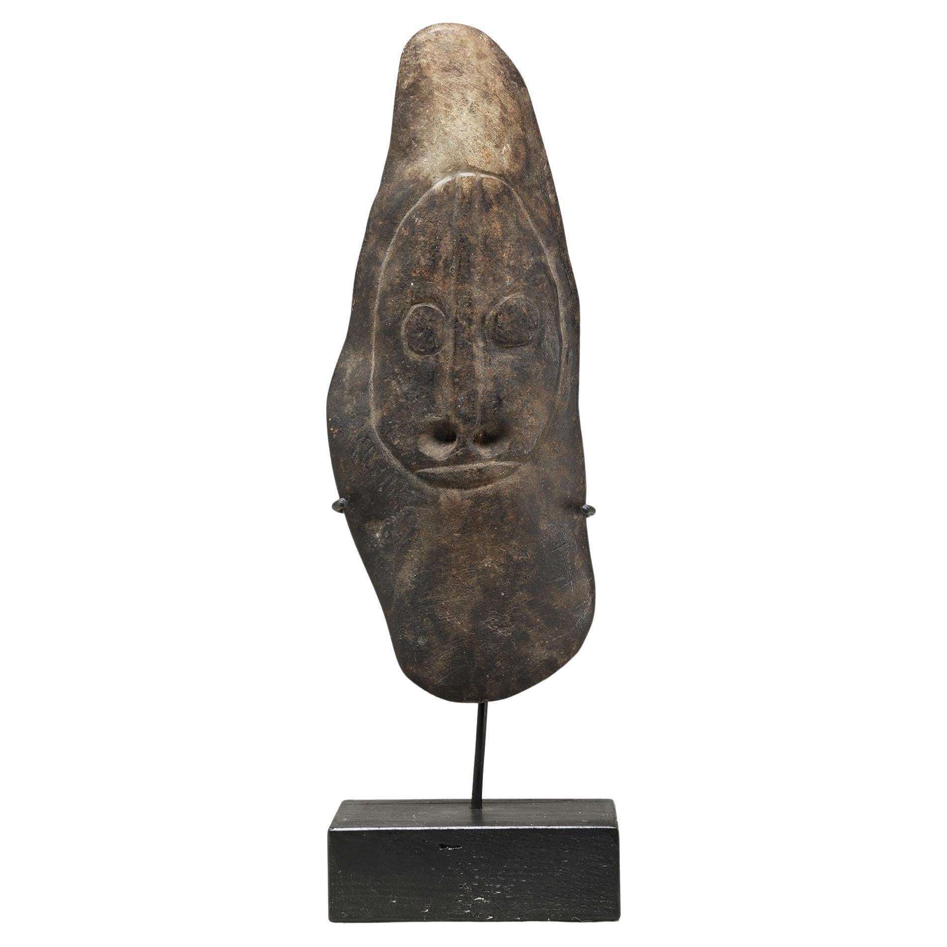Antigua hacha de piedra con la cara tallada y la nariz perforada, Papúa Nueva Guinea, sobre una base personalizada