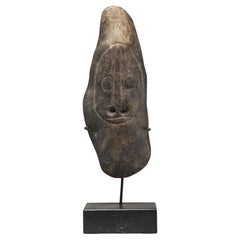 Antigua hacha de piedra con la cara tallada y la nariz perforada, Papúa Nueva Guinea, sobre una base personalizada