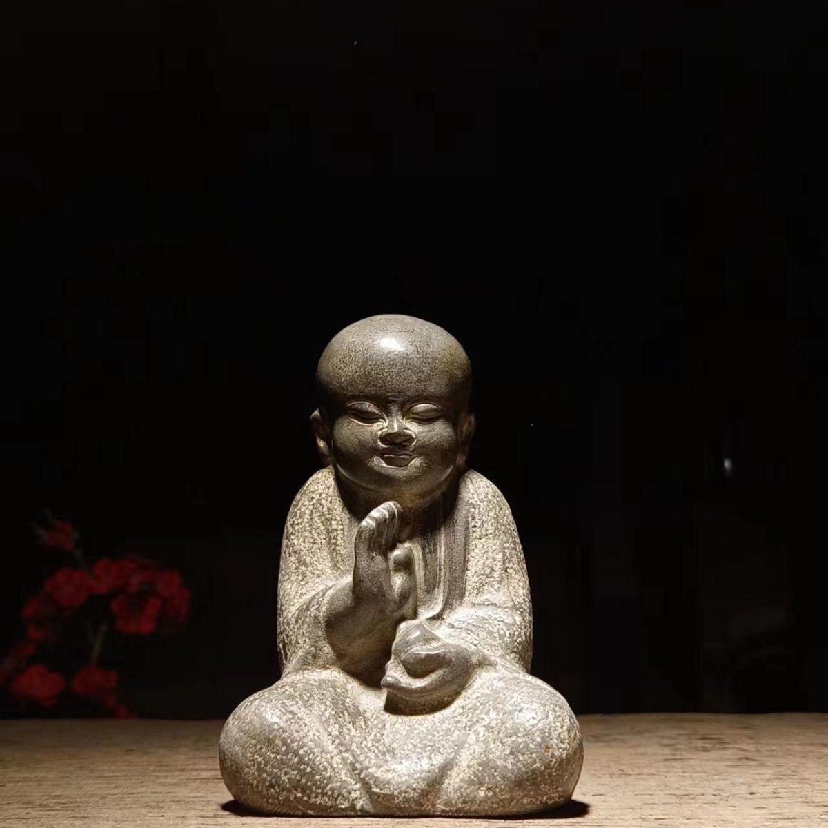 Une vieille sculpture en pierre représentant un jeune moine assis, une main levée, est un artefact symbolique et culturellement significatif qui représente un mélange de spiritualité, d'art et d'histoire.

La représentation d'un jeune moine