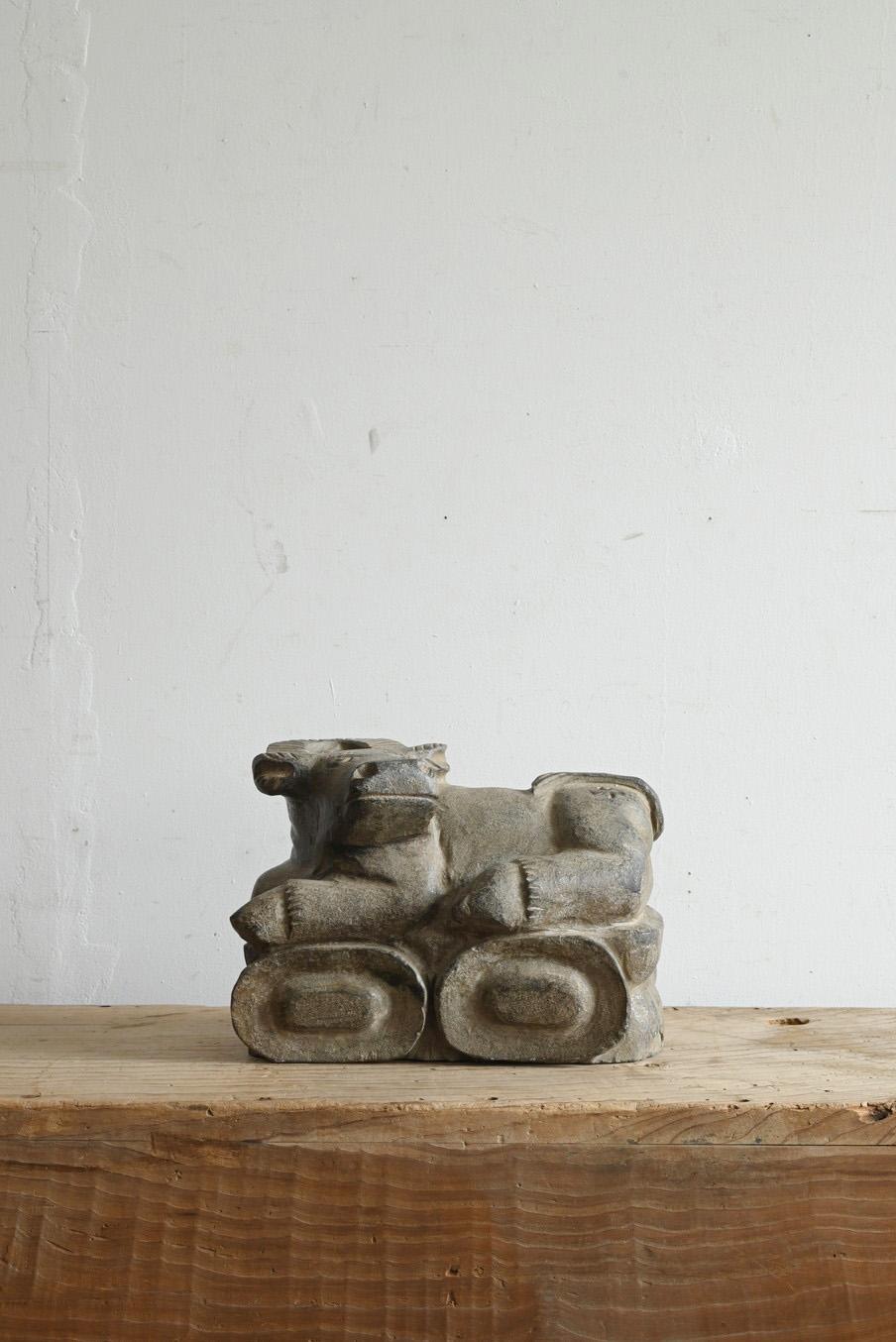 This is an old stone sculpture of a cow, believed to have been made in Korea or Japan. It is made of serpentine rock, which gives it a heavy weight and unique texture. In East Asian stone culture, serpentine rock has long been used as a material for