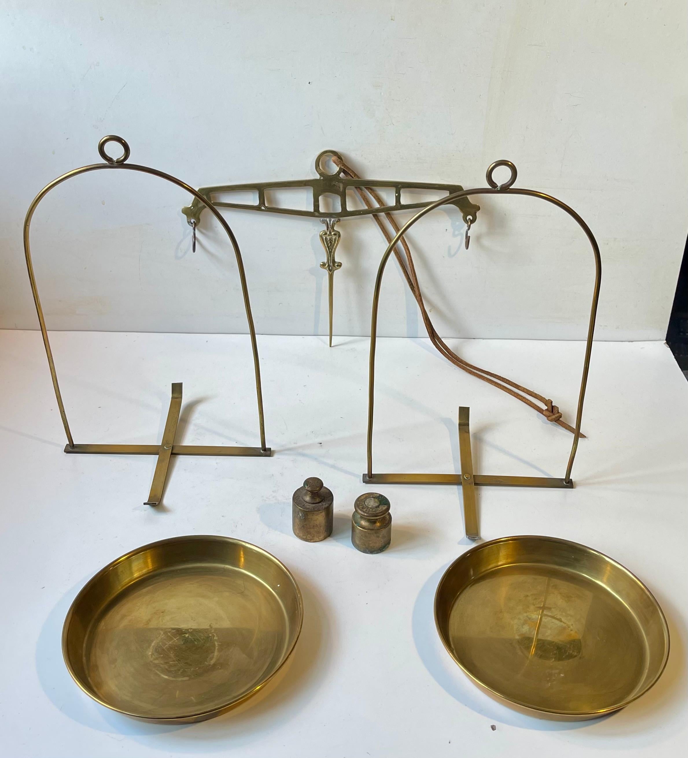 Balance décorative des années 1950 dans le style Apothicaire. Fabriqué en laiton massif, il est livré avec deux poids en laiton et une lanière de suspension en cuir. 

Dimensions : H/L : 75 cm (suspendu), Largeur : 30 cm, Dépt : 15 cm.