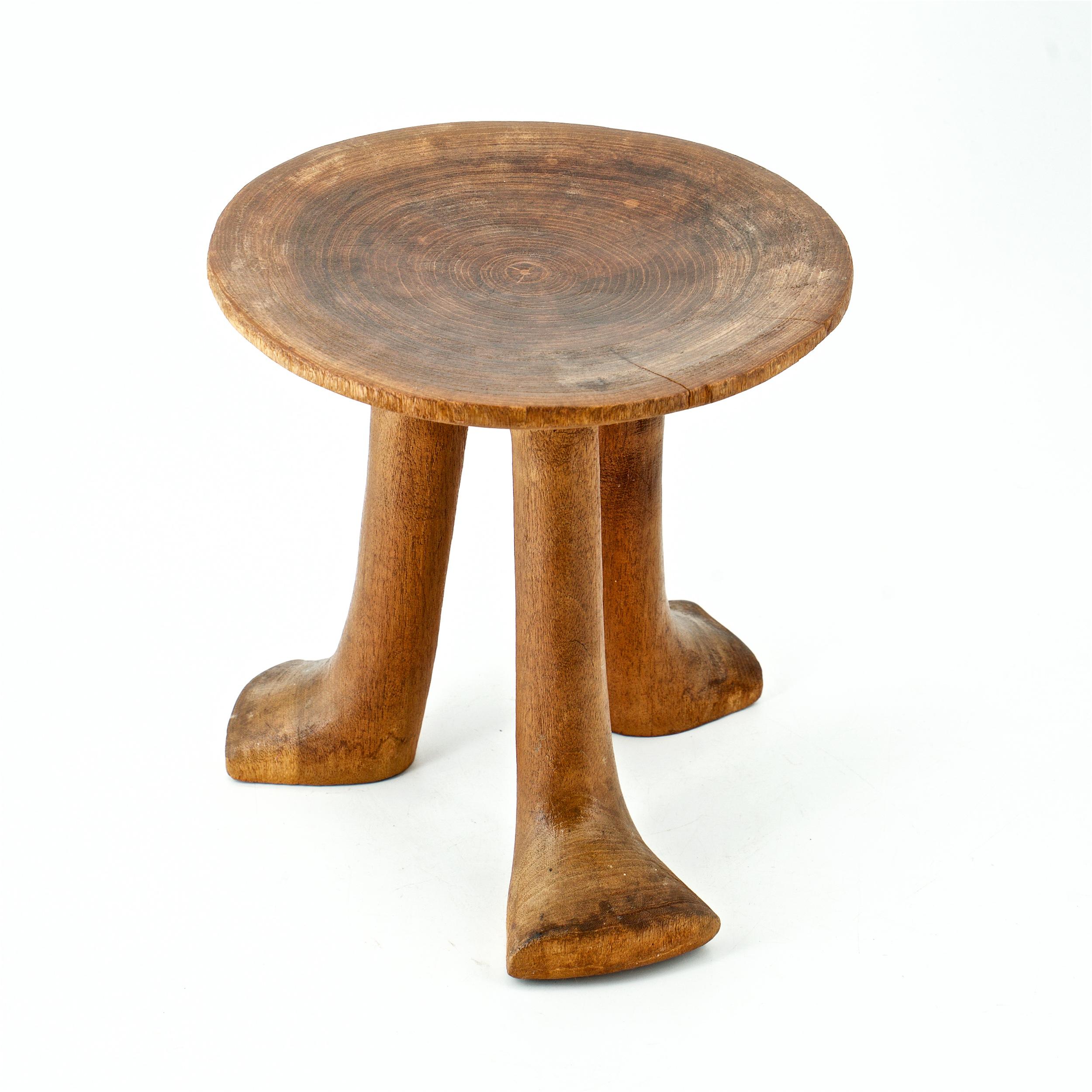 A teak tribal carved wood tripod stool, early to mid-20th Century. Origin unknown.