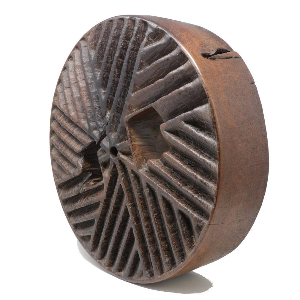 Old Thai Ironwood Millstone. A weathered solid thick piece of ironwood originally carved to create a deep track pattern on one side as the grinding surface, possibly used for the grinding of corn or shelling peanuts.  The millstone has been recently
