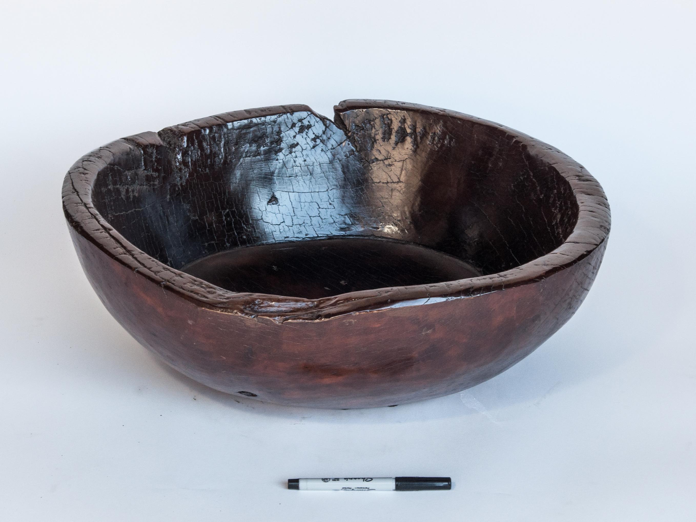 Old tribal wooden bowl from the Nepal Himal, mid-20th century. 20 inch diameter.
This bowl is hand hewn from a single piece of local hardwood. Years of use in the smokey interior of a Nepali house lend it a rich patina.
Condition: Structurally the