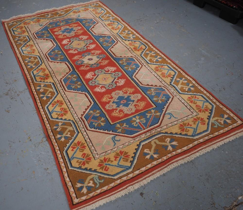 Antigua alfombra turca Milas de diseño tradicional y muy buenos colores suaves
Alrededor de 1960

La alfombra tiene cinco pequeñas rosetas florales sobre un fondo de color rojo muy suave Los bordes tradicionales en tonos pastel enmarcan bien la