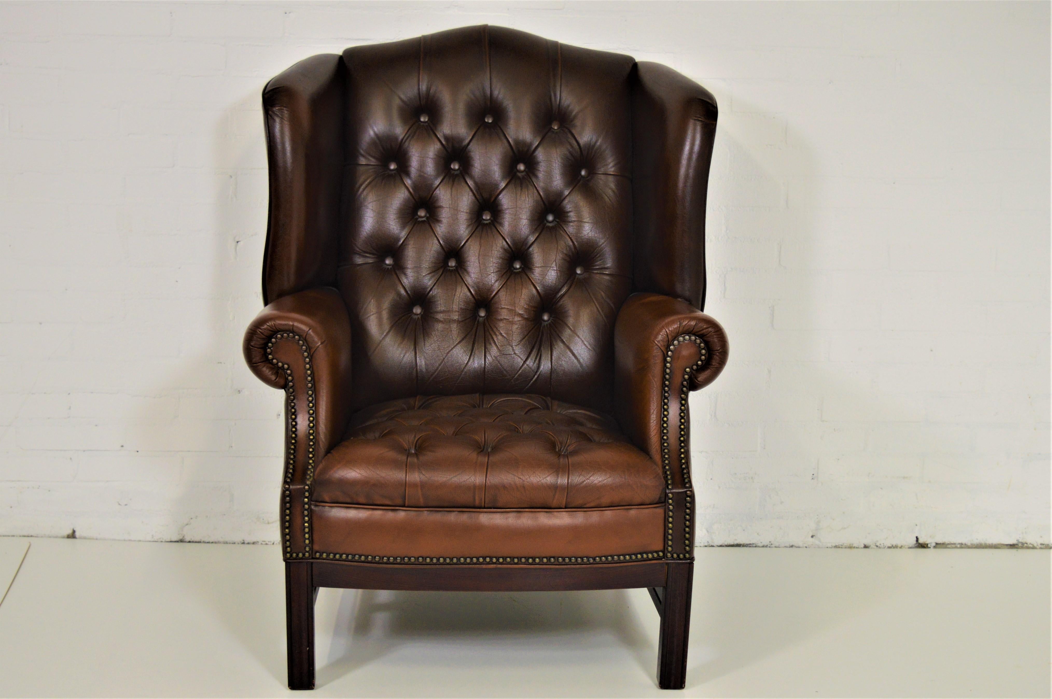Buttoned seat Chesterfield wing chair with real leather and brown color.

Antique brown high back chair or wing chair from 1963 sold to us by third owner who bought a brand new one exactly like this one. The chair comes with a nice price because