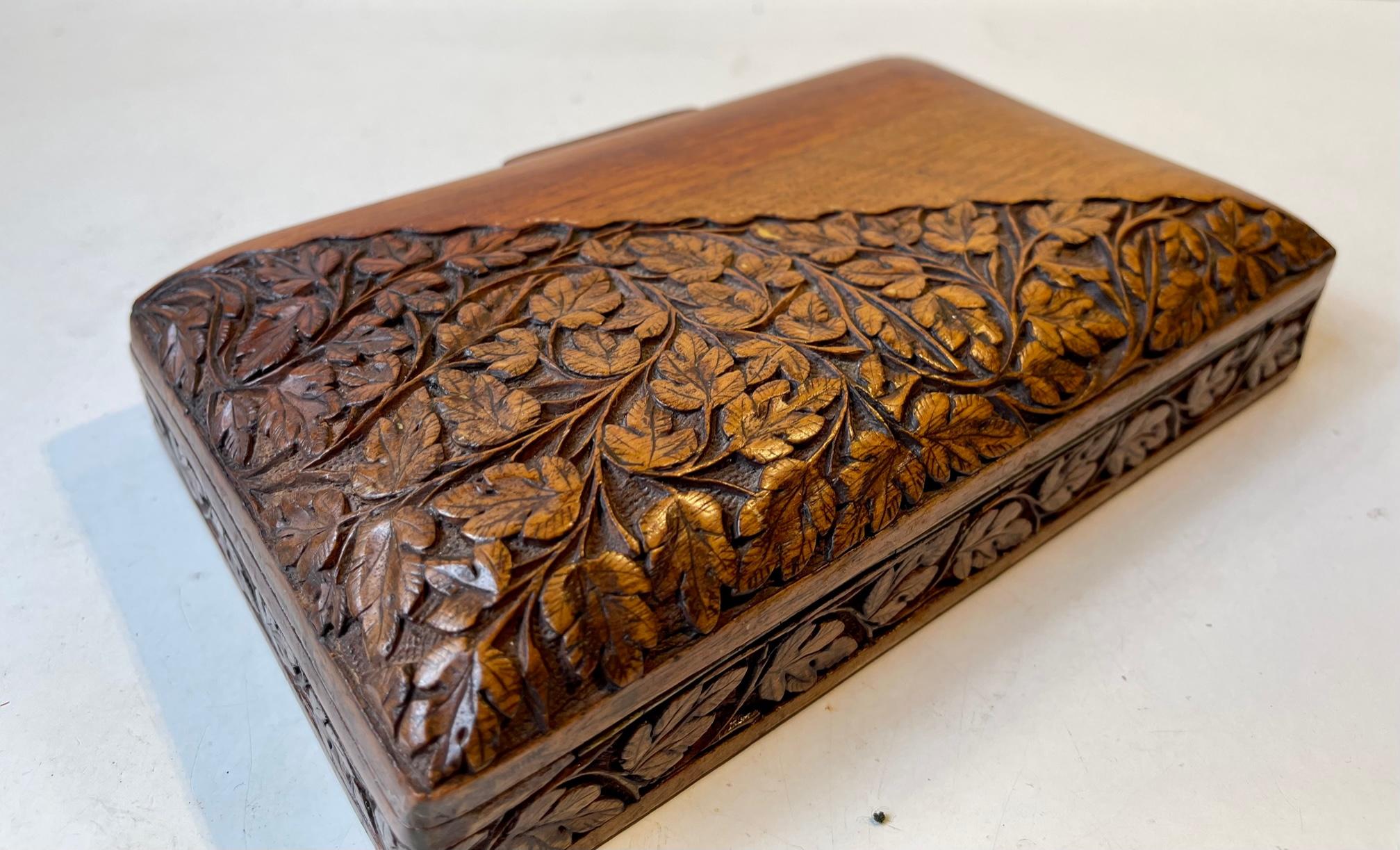 Dekoratives Eichenholzkästchen, das auf einer Hälfte aufwändig mit Eichenblättern verziert ist. In den 1920er Jahren in Skandinavien handwerklich hergestellt. Geeignet für Tabak, Schmuck oder Spielkarten. Abmessungen: 20x12,5x5 cm.