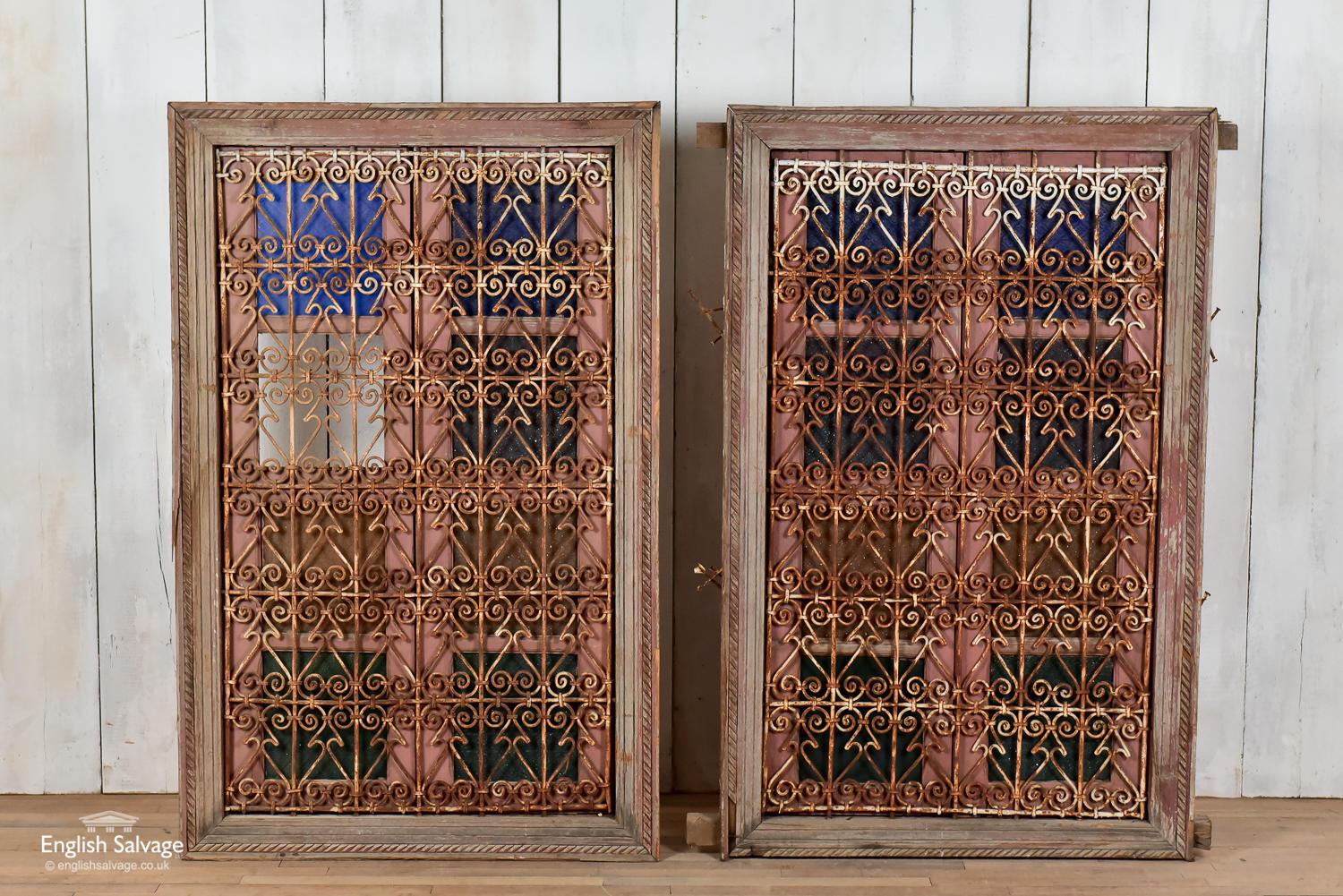 Reclaimed Moroccan windows with iron scroll bars, wooden shutters and colored glass. Measures: Overall: 90cm x 141cm x 9cm. Opening 74cm x 125cm. Some scuffs and splits commensurate with age. Window with all glass panels intact remaining.