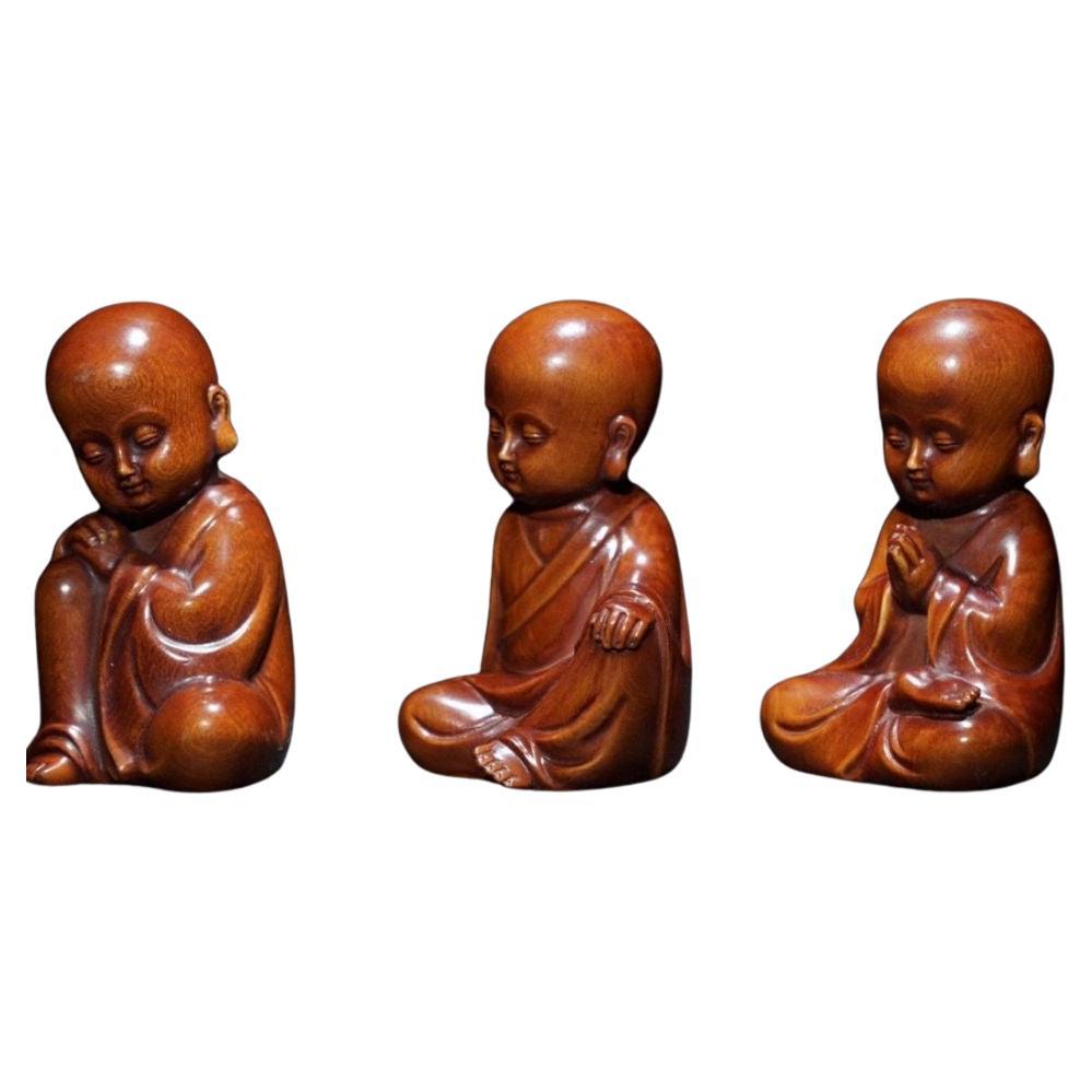 Conjunto de estatuas talladas en madera antigua de tres pequeños monjes asiáticos