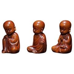 Conjunto de estatuas talladas en madera antigua de tres pequeños monjes asiáticos