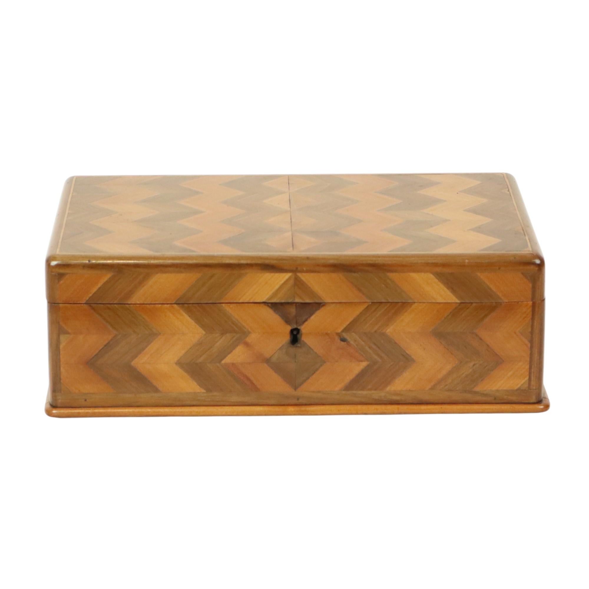 Antica scatola di legno, portagioie o gingilli in legno intarsiato, intarsiata con un disegno geometrico a chevron, circa metà del XX secolo.

Questa scatola di legno è di alta qualità ed è una gioia per gli occhi. Il bellissimo motivo a chevron o a