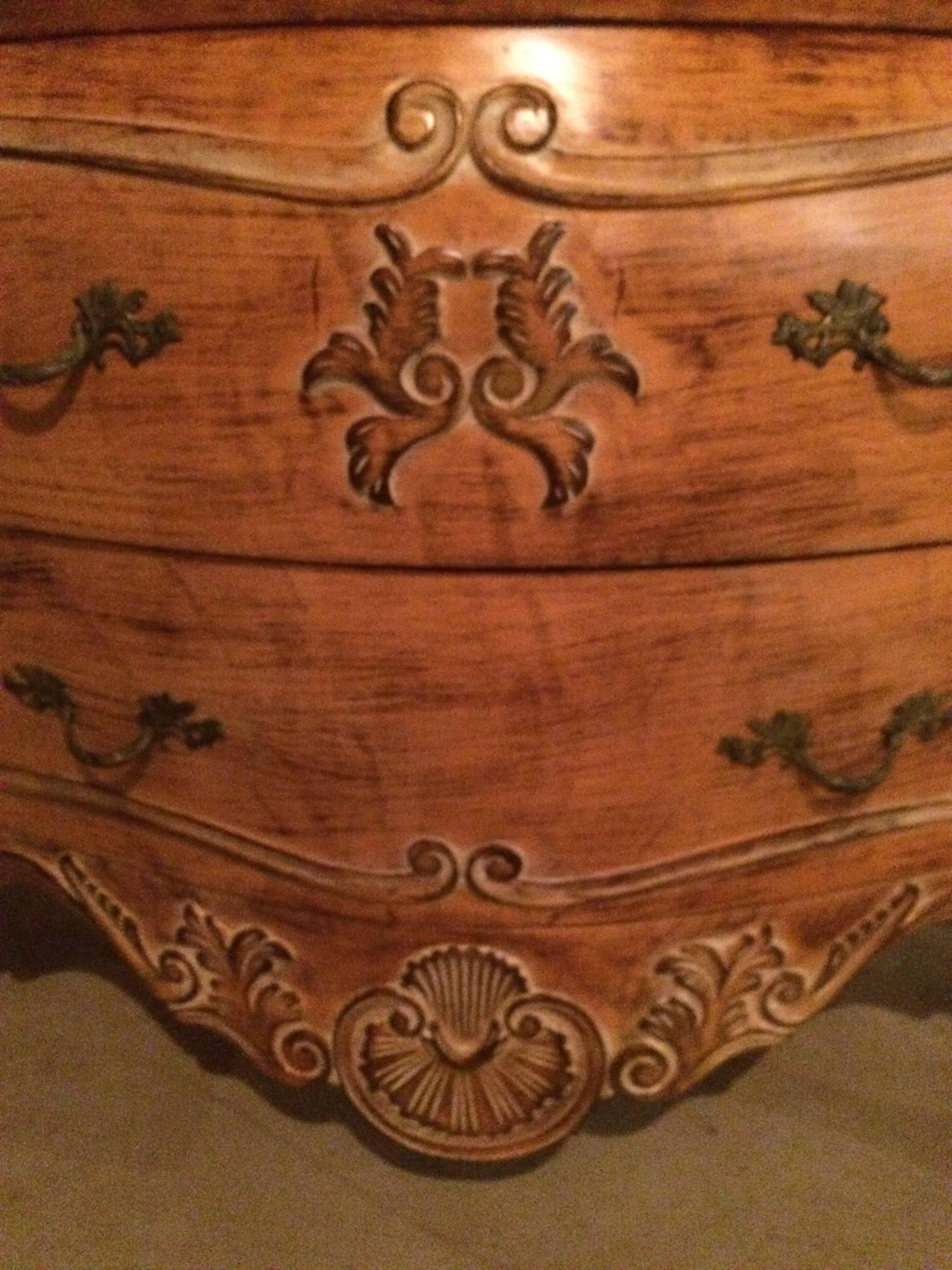 Magnifique commode bombe en bois sculpté avec un dessus en marbre crème ayant un motif de coquille et deux tiroirs spacieux.