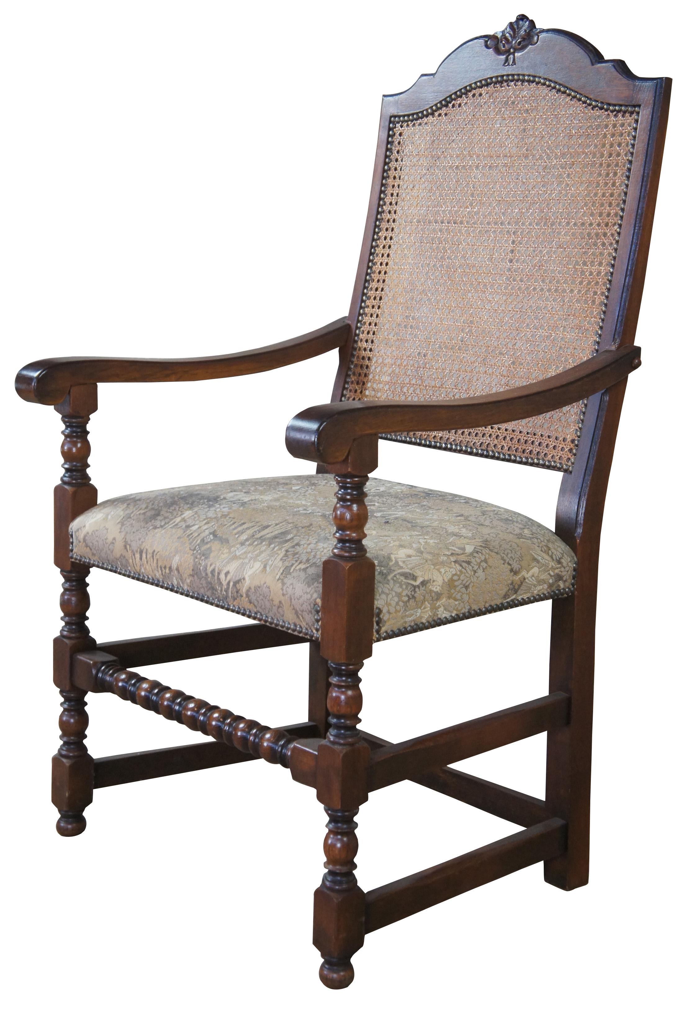 Vintage Spanish Revival arm or accent chair. Made of oak, featuring a caned back, upholstered aubusson style seat with nailhead trim and turned posts.
  