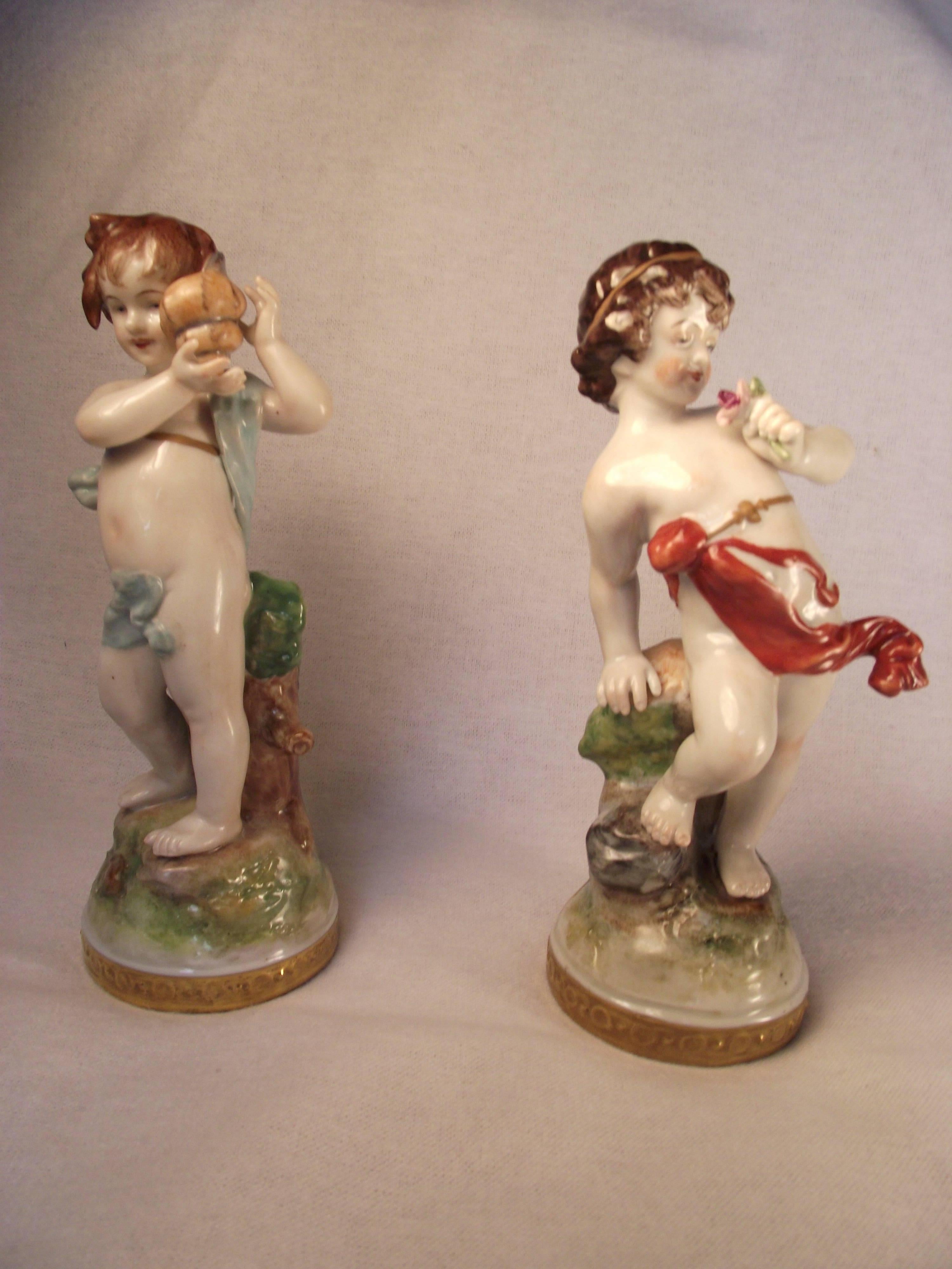 Two charming antique figurines in absolutely perfect condition bearing the oldest Volkstedt Factory Porcelain mark. One is holding flowers and one listening to a sea shell. Exquisitely hand-painted with gold trimmed base. No chips scratches or