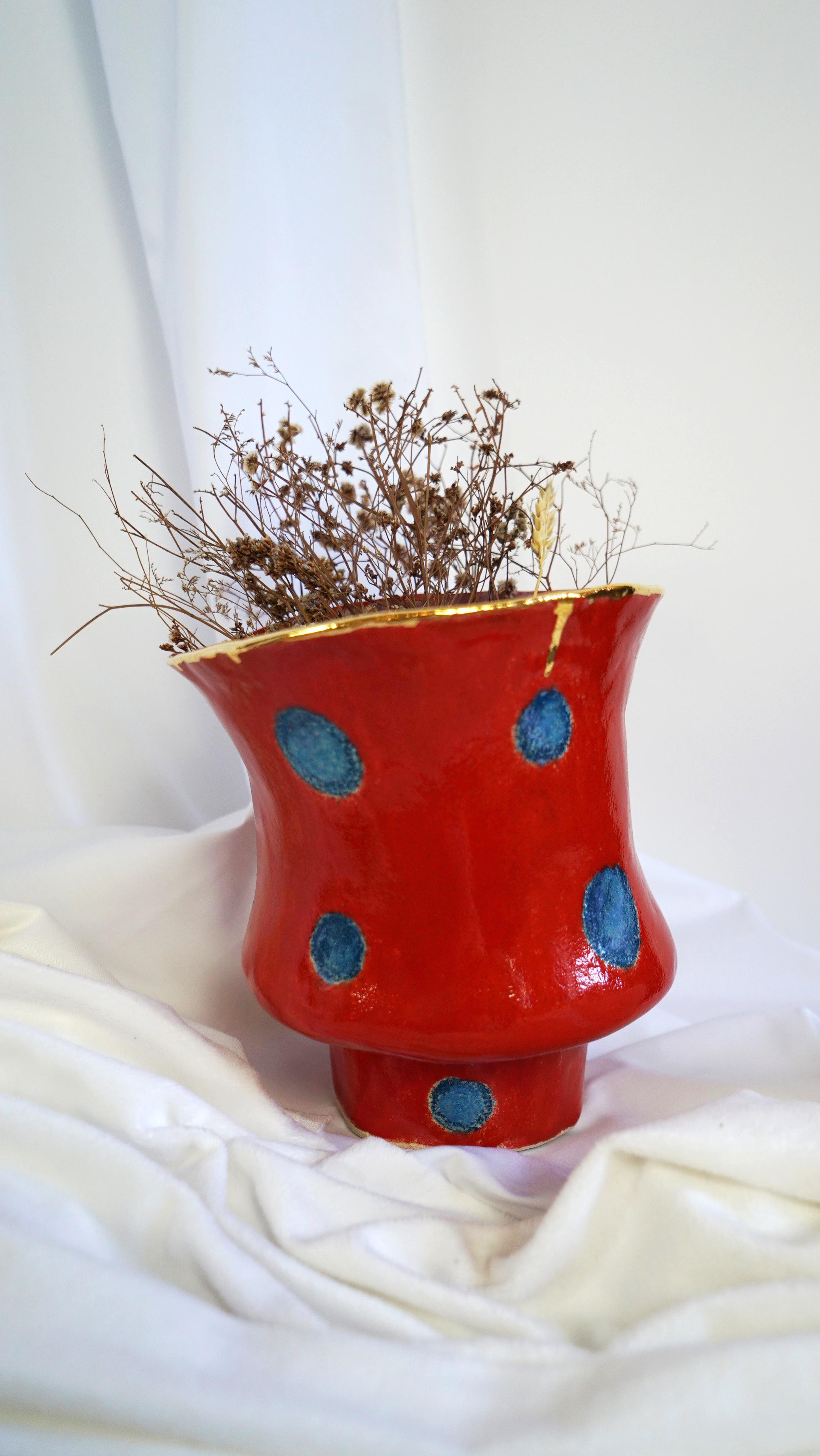 Olé 5 Vase by Hania Jneid
Unique Piece.
Dimensions: Ø 20 x H 20 cm.
Materials: Stoneware, glaze and gold luster.

Numbered Olé Vase in the collection Olé, a tribute to the Flamenco culture. Color: Red on blue sketchy dots, Gold luster, Violet