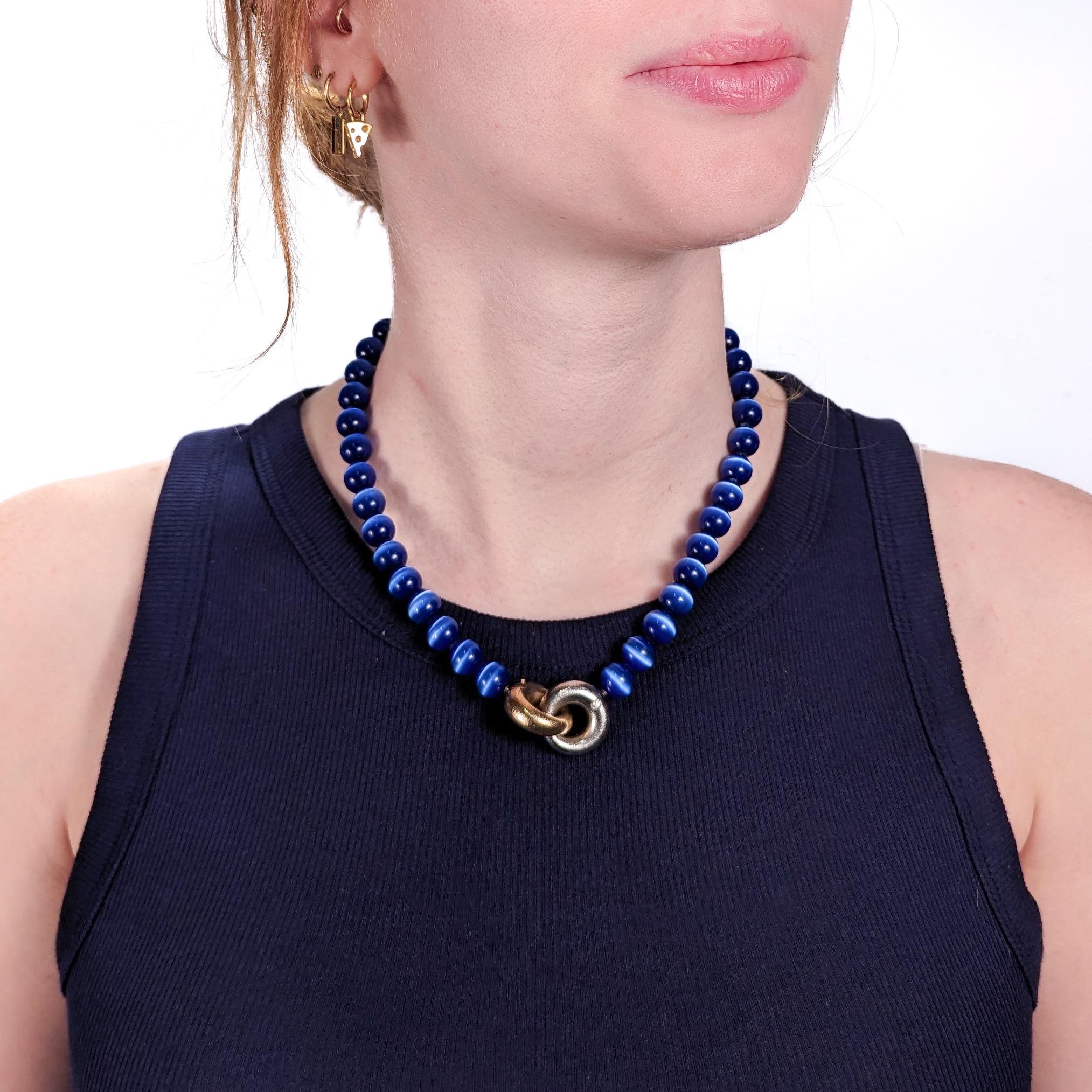 A very fine Ole Lynggaard collier or choker necklace.

With deep blue tiger's eye (or hawk's eye) beads.

Secured with yellow and white 18k gold hollow gold clasp shaped as interlocking rings that are each flush set with a round brilliant cut white