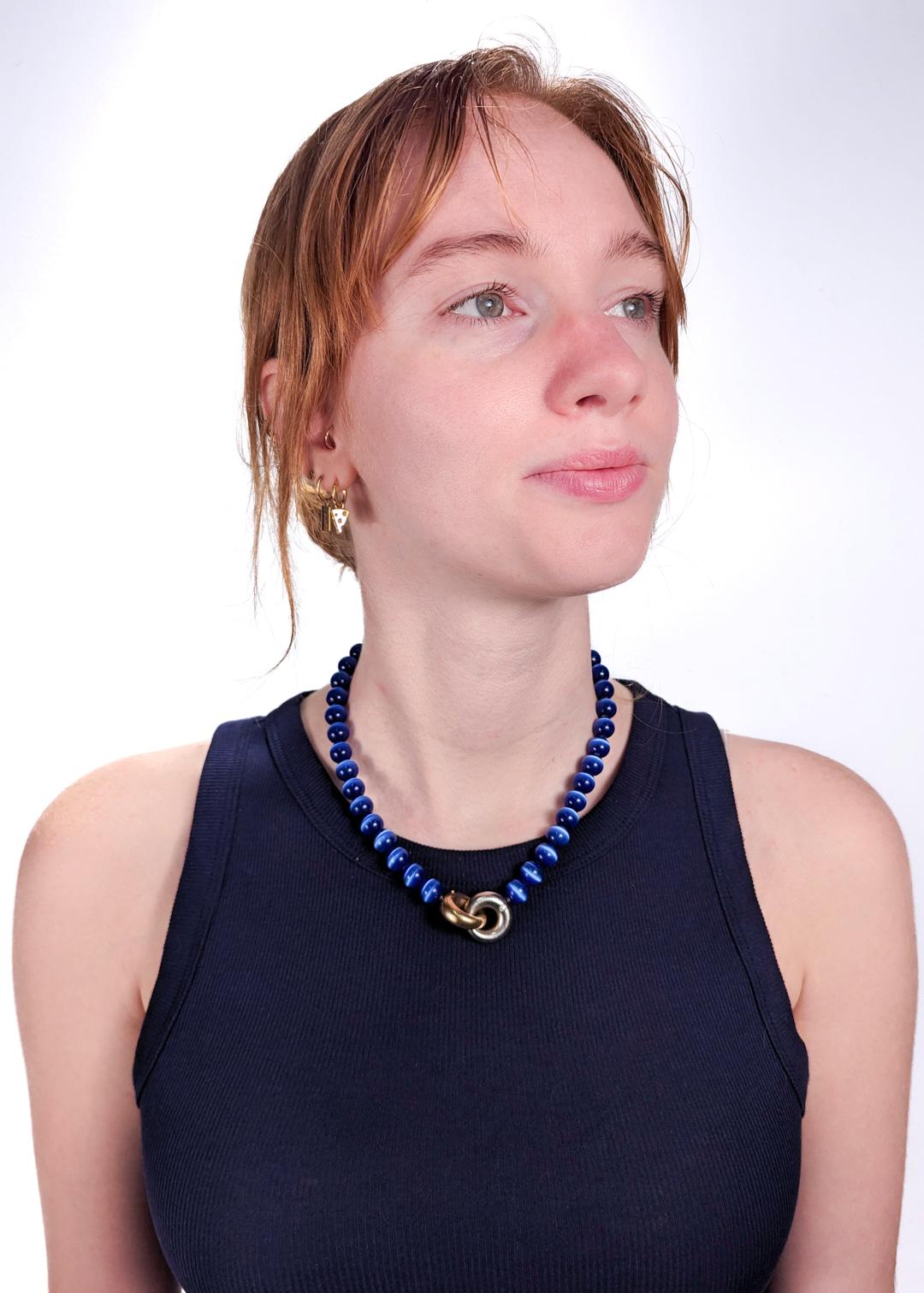A very fine Ole Lynggaard collier or choker necklace.

With deep blue tiger's eye (or hawk's eye) beads.

Secured with yellow and white 18k gold hollow gold clasp shaped as interlocking rings that are each flush set with a round brilliant cut white