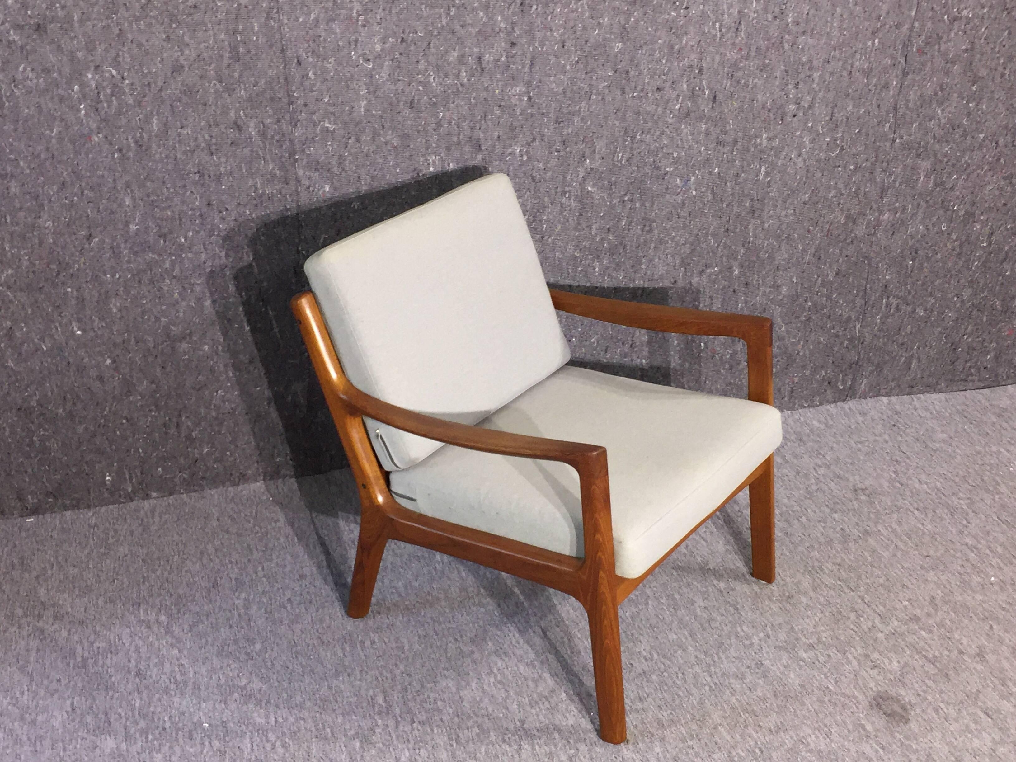 This lounge chair was designed by Ole Wancher in 1951 for Cado (France & Søn) in Denmark. The frame is made in solid teak with spherical armrest. The frames are dowelled and screwed to the side elements, upholstery in light fabric.