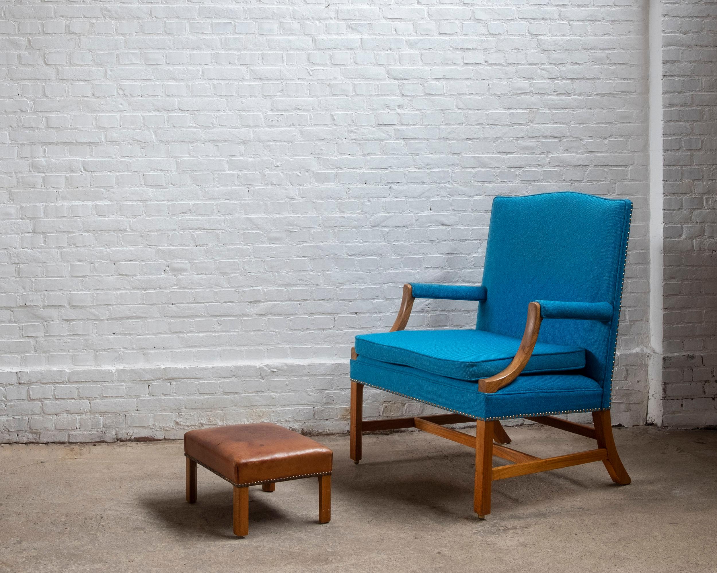 An easy chair and ottoman attributed to Ole Wanscher, the frames are made from mahogany, the chair is later reupholstered with a high quality blueish fabric, the ottoman still has the original patinated leather. Both pieces are numbered and marked