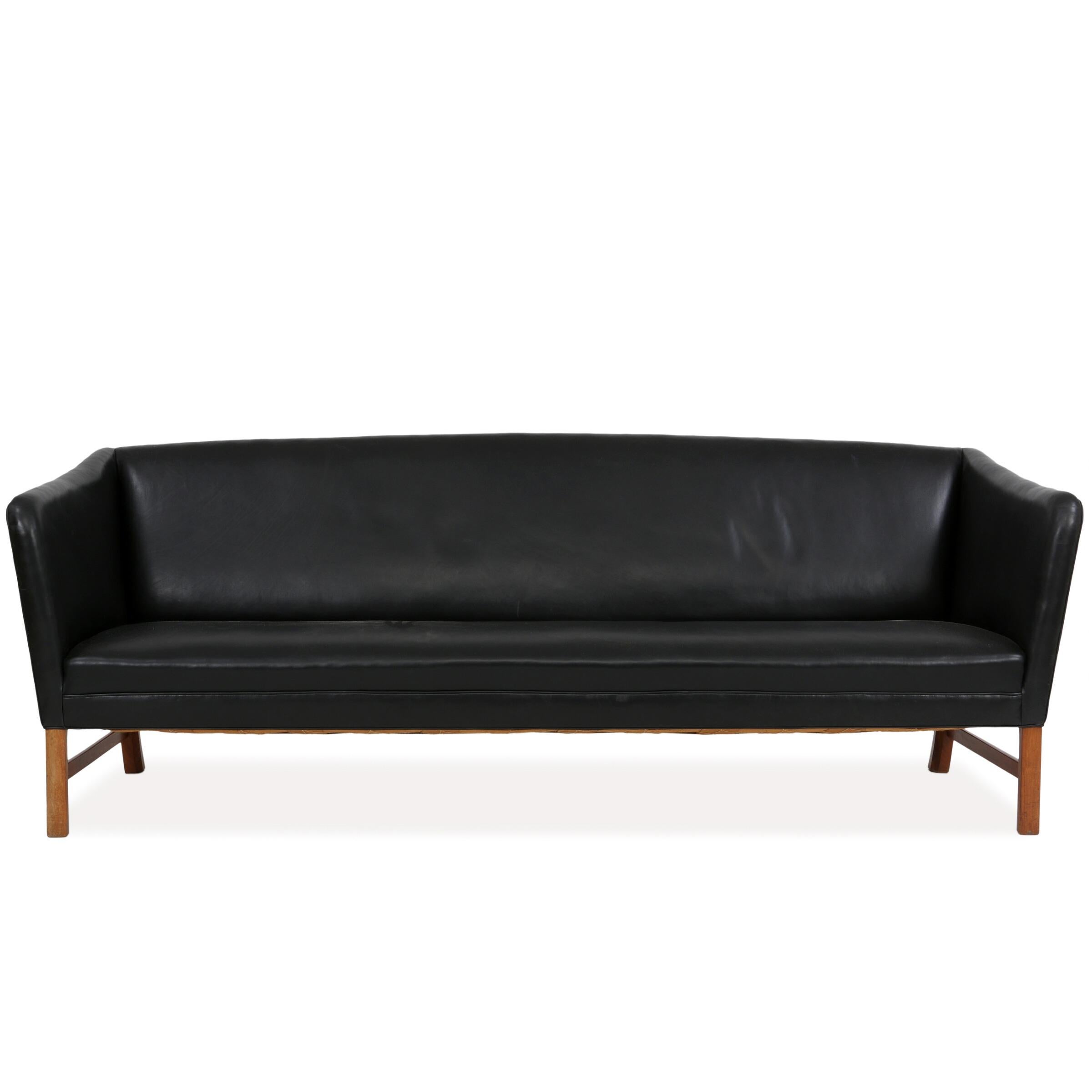 Freestanding three seater sofa with mahogany frame designed by Ole Wanscher. Sides, seat and back upholstered with black leather. This example made 1960s by cabinetmaker A.J. Iversen. Measures: H. 79 cm. L. 209 cm. Seat H. 40 cm. D. 80