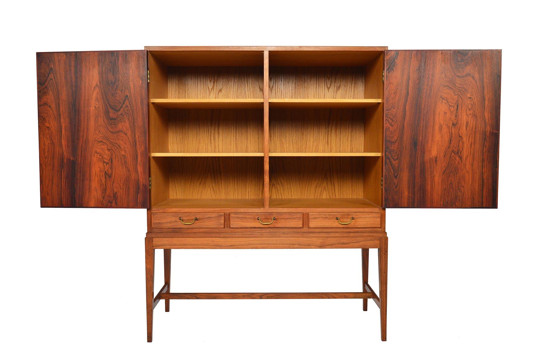 This Danish modern Brazilian rosewood cupboard by Ole Wanscher is an incredibly versatile storage piece- perfect for use as a dry bar! Stunning patinated rosewood offers a light, grain- rich finish only decades of careful stewardship can provide.