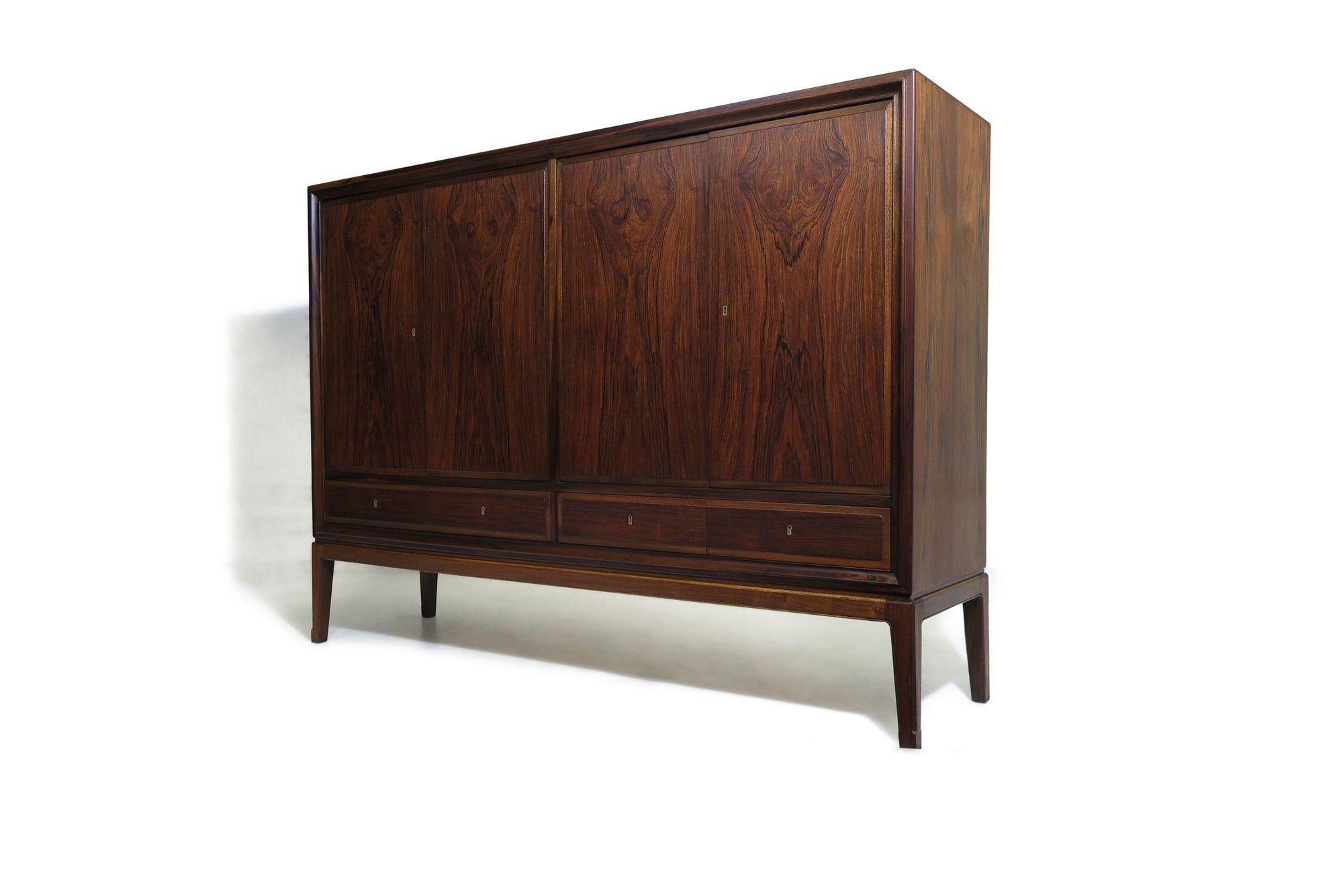 Brazilian Rosewood sideboard designed by Ole Wanscher, 1955: a timeless masterpiece showcasing the unparalleled craftsmanship of midcentury Danish design. Features rich, unfaded, Brazilian rosewood, with book-matched locking doors and drawers. The