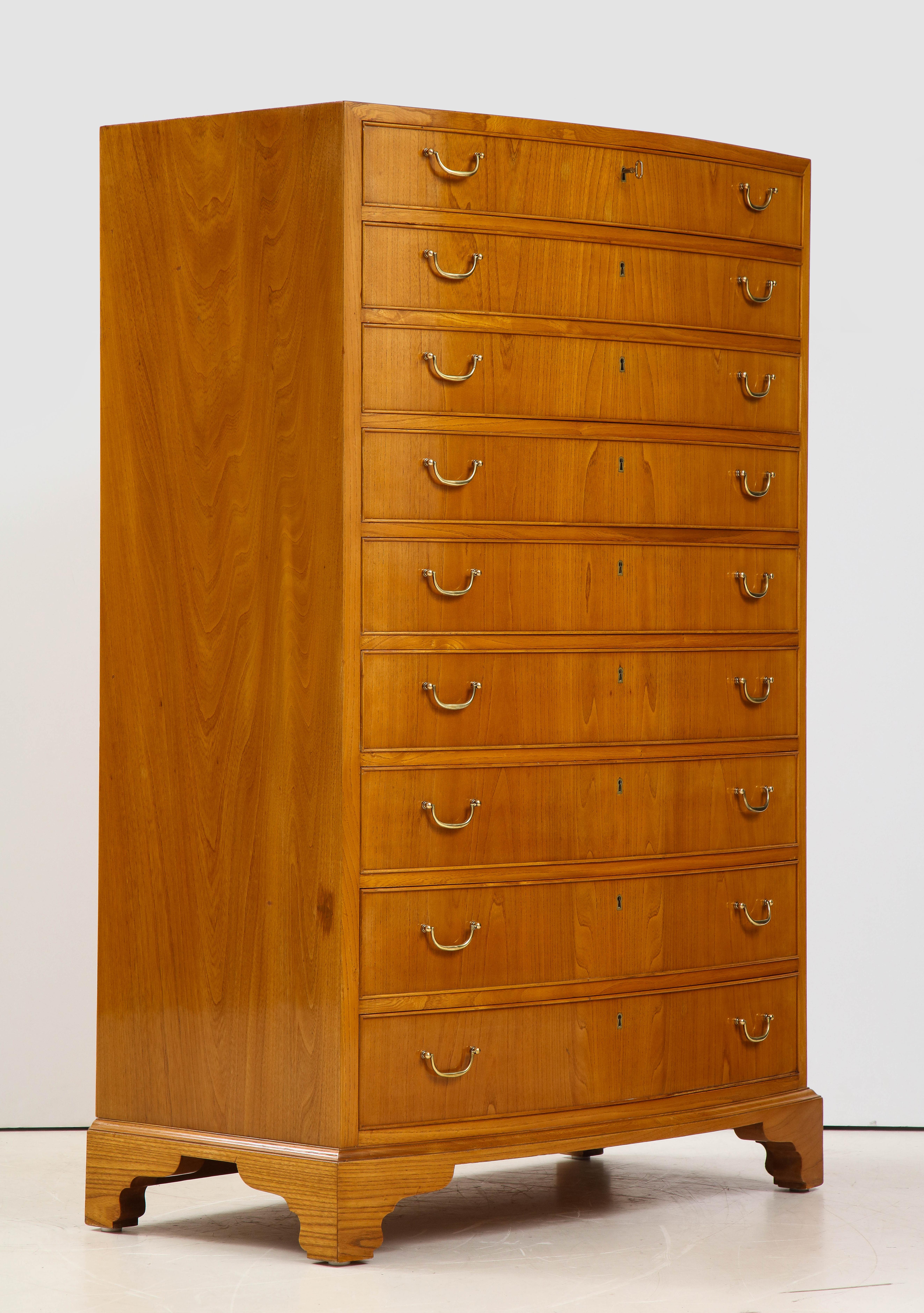 A Danish modern elmwood tall bow-front chest of drawers by Ole Wanscher, circa 1950s with nine bow front graduated drawers raised on scrolled bracket feet.