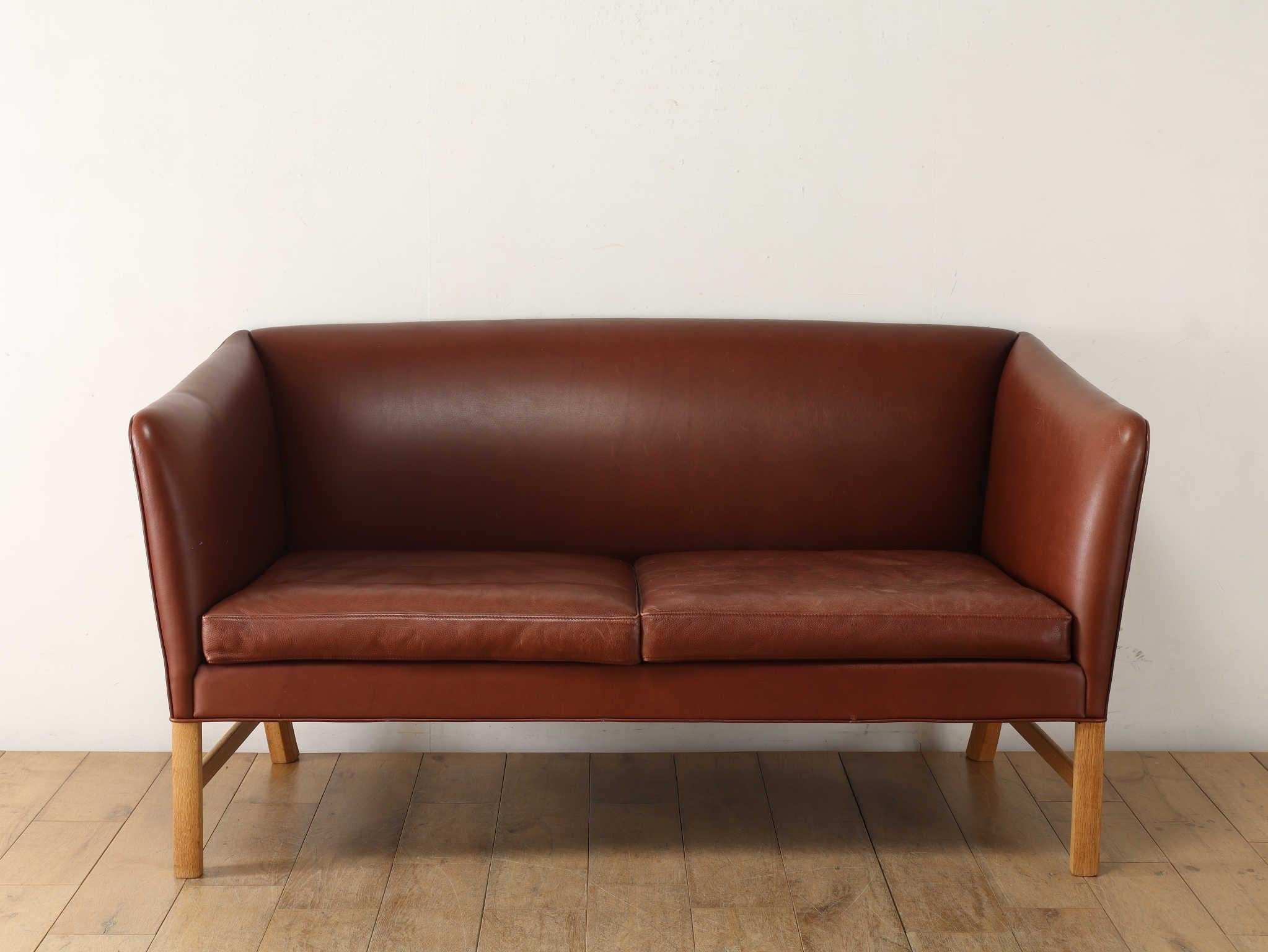 This two-seat leather sofa was created by Scandinavian furniture design master Ole Wanscher in the 1950s. It is characterised by its elegant and refined form, which seems to embody his philosophy that 