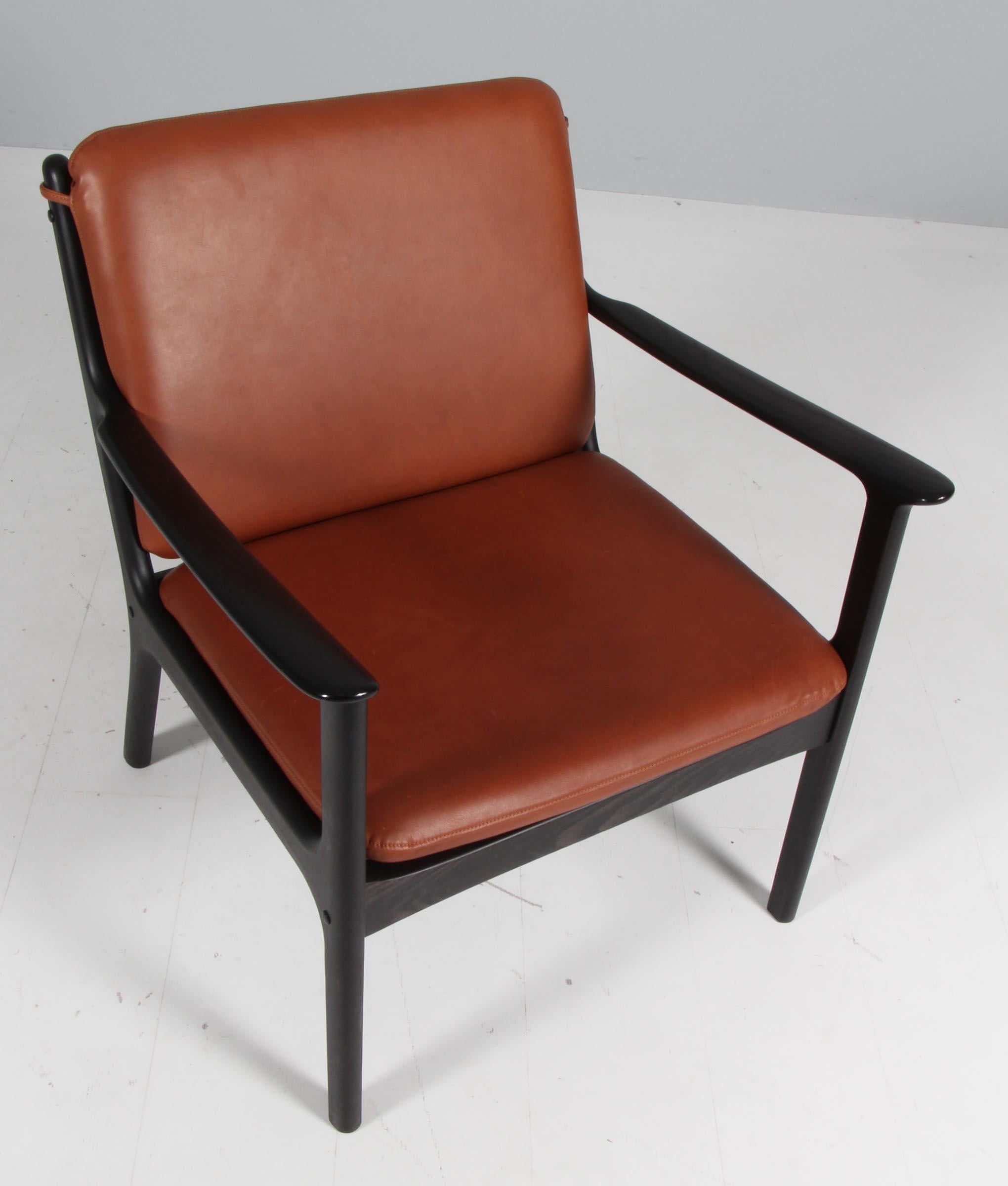 Chaise de salon Ole Wanscher neuve, recouverte de cuir aniline couleur brandy. 

Fabriqué en frêne massif teinté.

Modèle PJ 112, fabriqué par Poul Jeppesen.

 