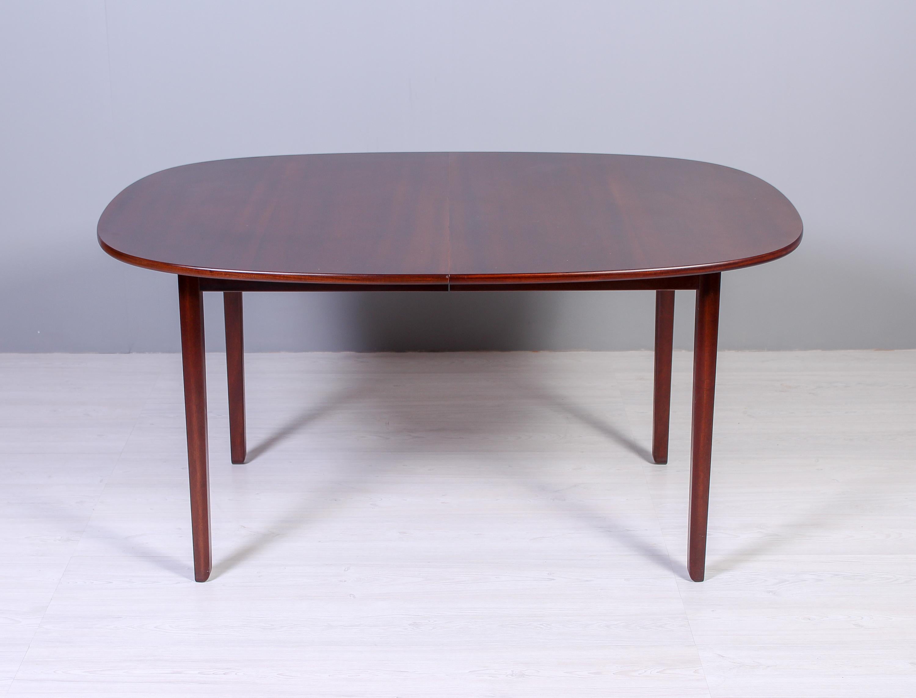 A oval dining table in high quality mahogany by Danish designer Ole Wanscher. This dining table is a part of a line of furniture by Wanscher called Rungstedlund and was designed in the 1960s. Produced by Paul Jeppesen. The table has two extra leaves