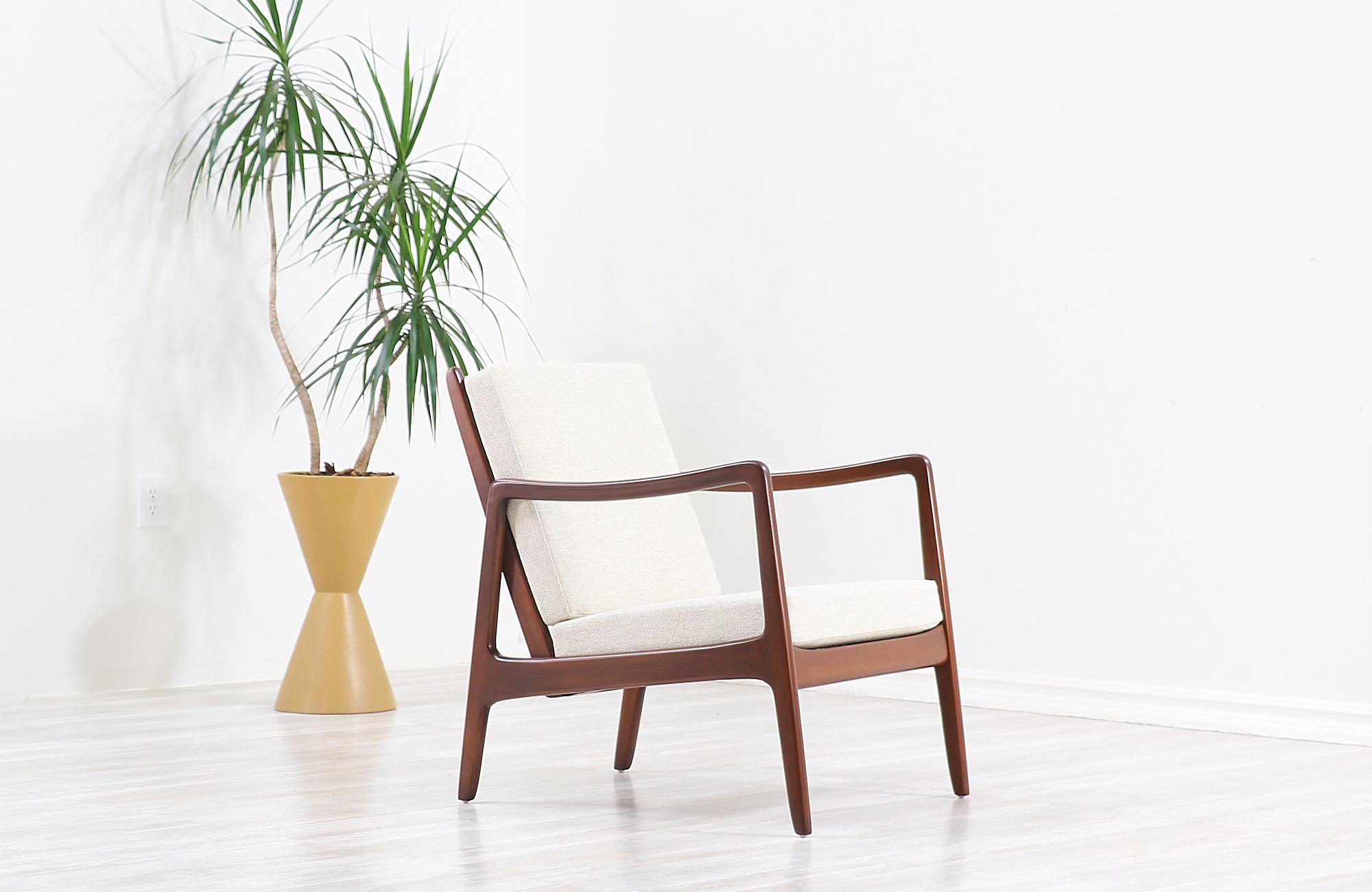 Elegant lounge chair designed by Ole Wanscher for France & Søn in Denmark, circa 1950s. This rare vintage model FD-109 lounge chair maintains the manufacturer’s mark and features a sturdy walnut-stained beechwood frame with a slated open back and