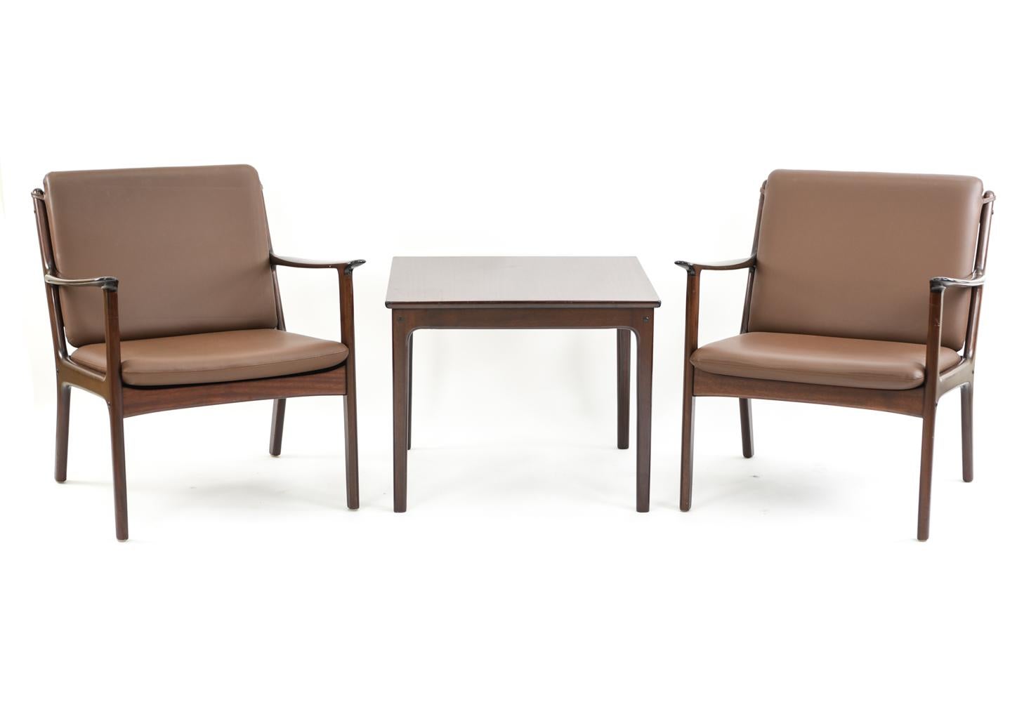 This lounge suite was designed by Ole Wanscher for Poul Jeppesen. These model PJ112 lounge chairs are complemented by the matching side table. All with mahogany frames, these chairs and table make a cohesive collection to unify a living space.