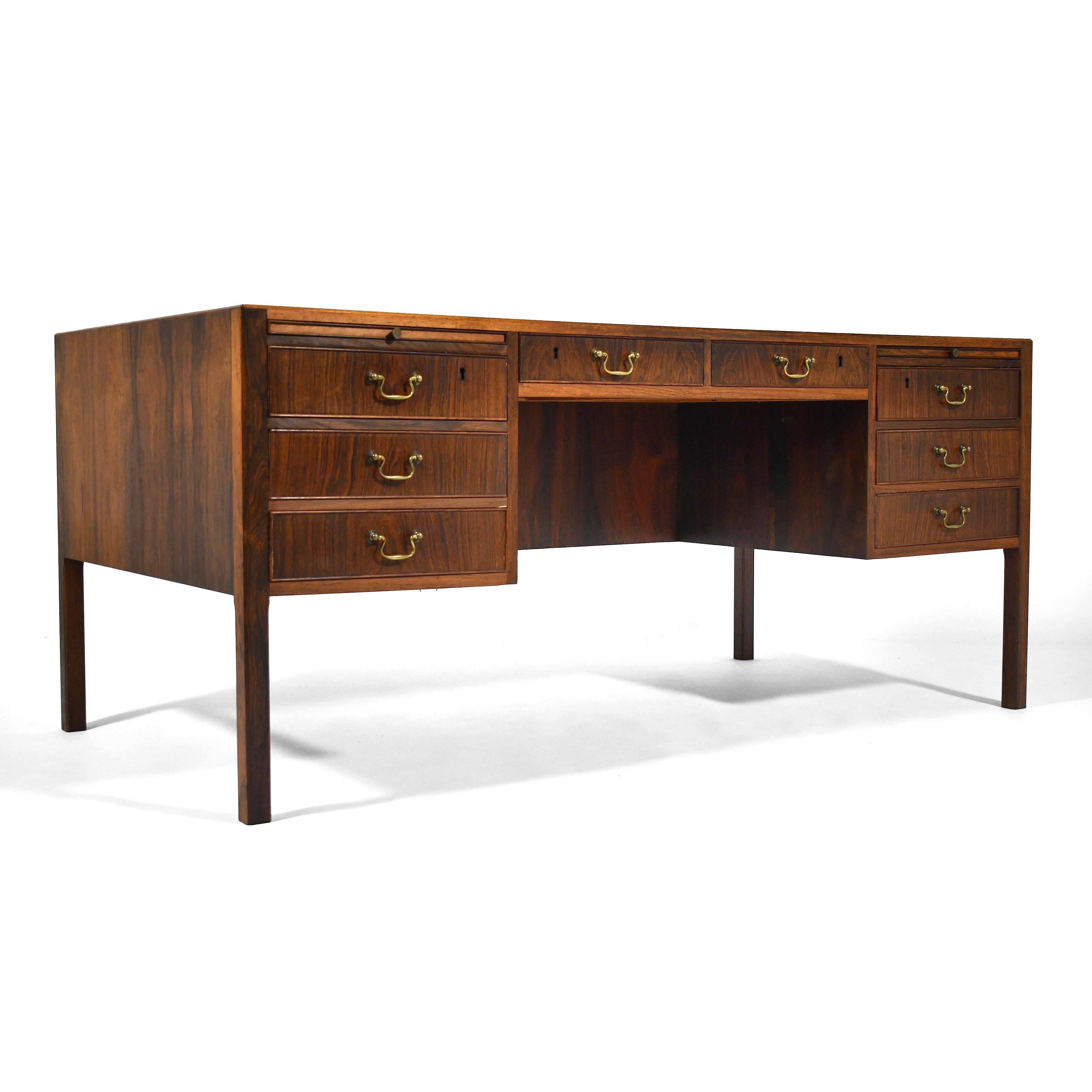 This 1950s Ole Wanscher design by A.J. Iversen is a transitional piece, combining traditional elements of a double pedestal desk with a decidedly modern approach.

The most striking feature is the beautiful, highly figured rosewood that it is clad