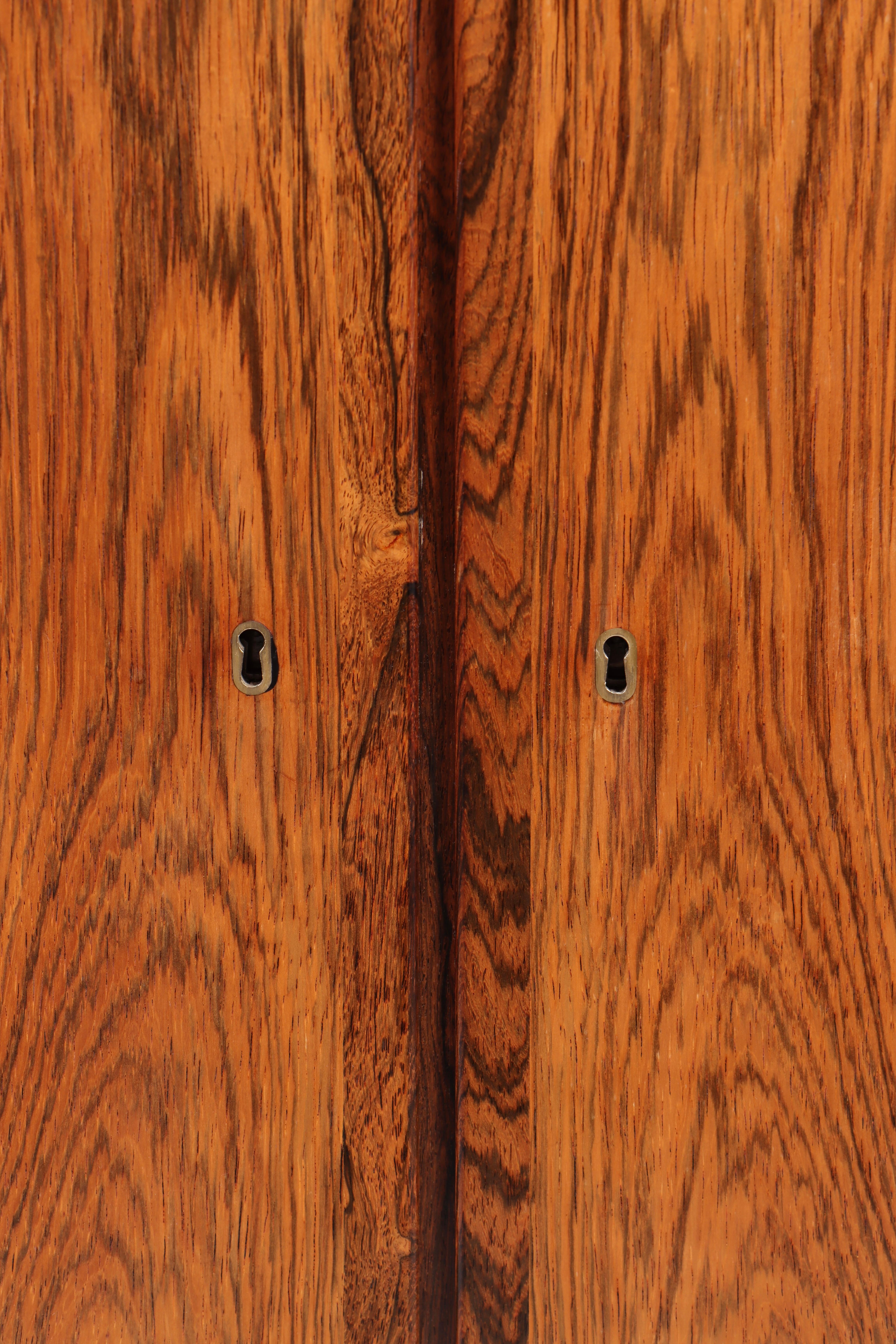 Elegant and rare high cabinet designed by Danish professor and architect Ole Wanscher and manufactured by P. Jeppesen in Denmark, 1960s. Crafted in beautifully grained Brazilian rosewood (palisander), the cabinet features double doors with stunning