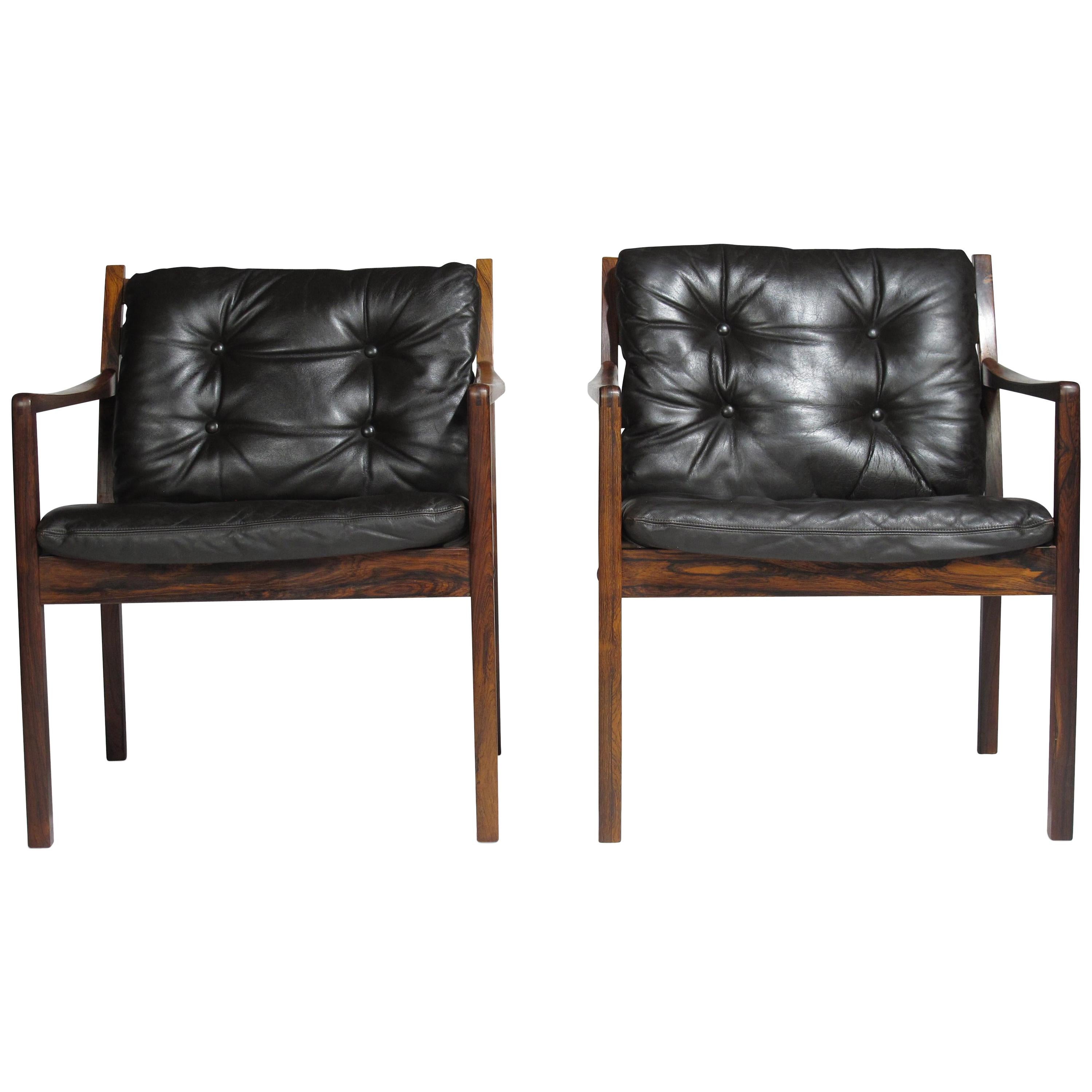 Midcentury Brazilian rosewood lounge chairs attributed to Ole Wanscher. Each lounge chair crafted of rich dynamic grained Brazilian rosewood with exposed joinery in arms, slatted backrest and loose cushions covered in the original black leather with