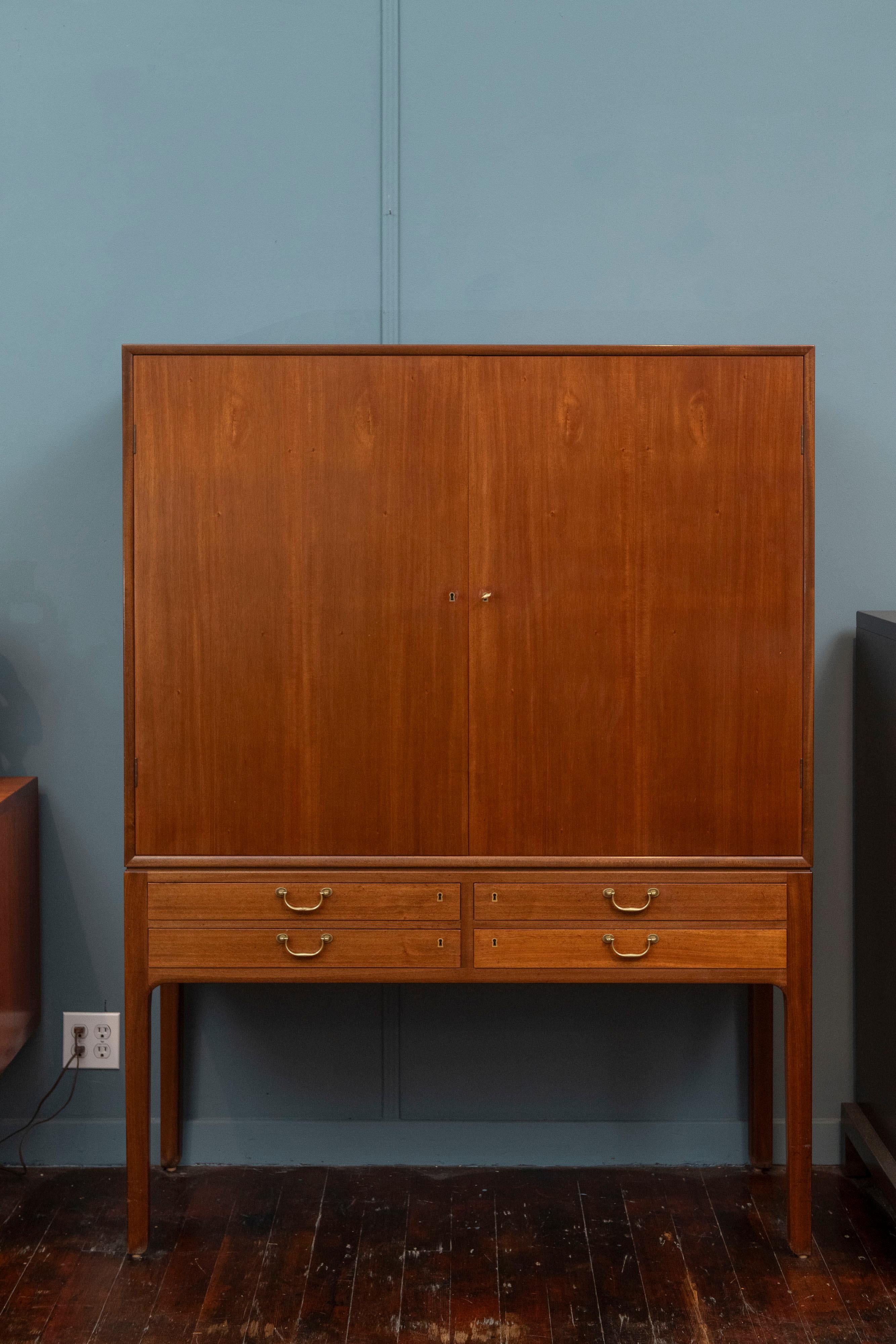 Ole Wanscher design tall cabinet for A.J. Iversen, Denmark. High quality construction and material executed in a refined Scandinavian aesthetic. mahogany case with brass drawer pulls and locking key. Two upper doors reveal six matching adjustable