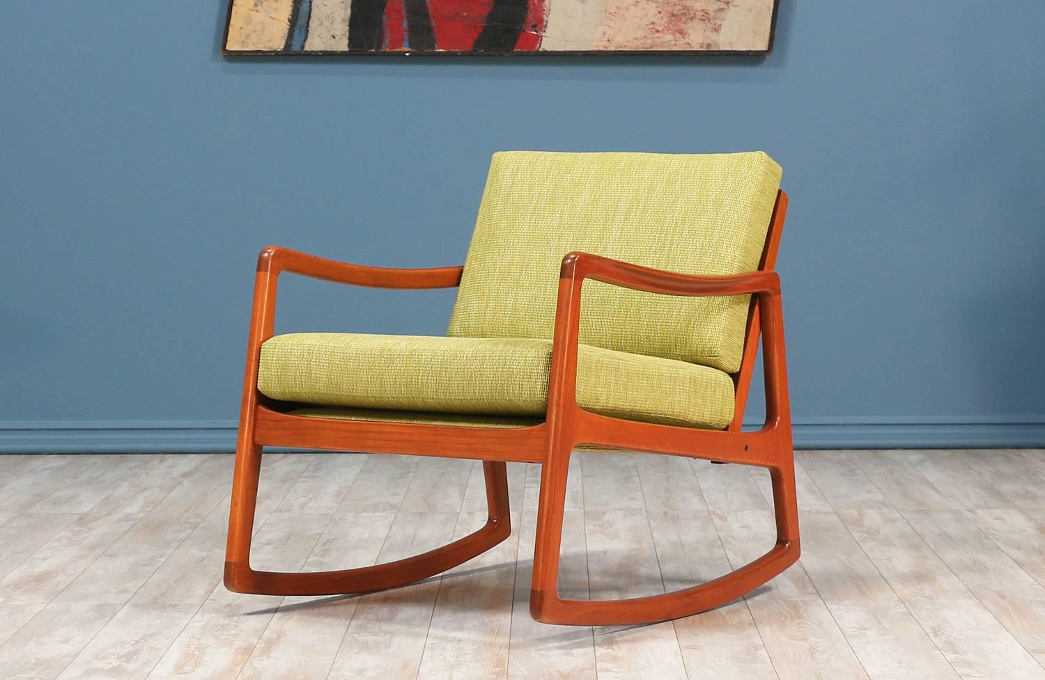 Rocking Chair designed by Ole Wanscher for France & Søn in Denmark circa 1950’s. This beautiful Danish modern design features a solid teakwood frame that maintains the manufacturer label on the back. Features comfortable curvilinear arm rests and a