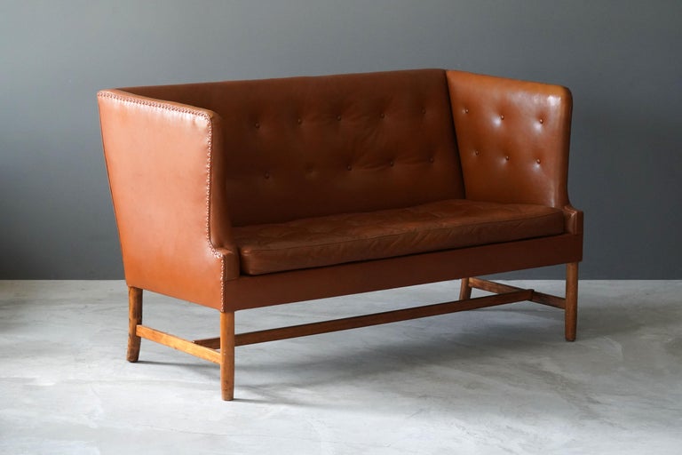 A rare two-seat sofa / settee / loveseat. Designed by Ole Wanscher for A.J. Iversen, Denmark, 1940s-1950s.

In leather and stained wood.