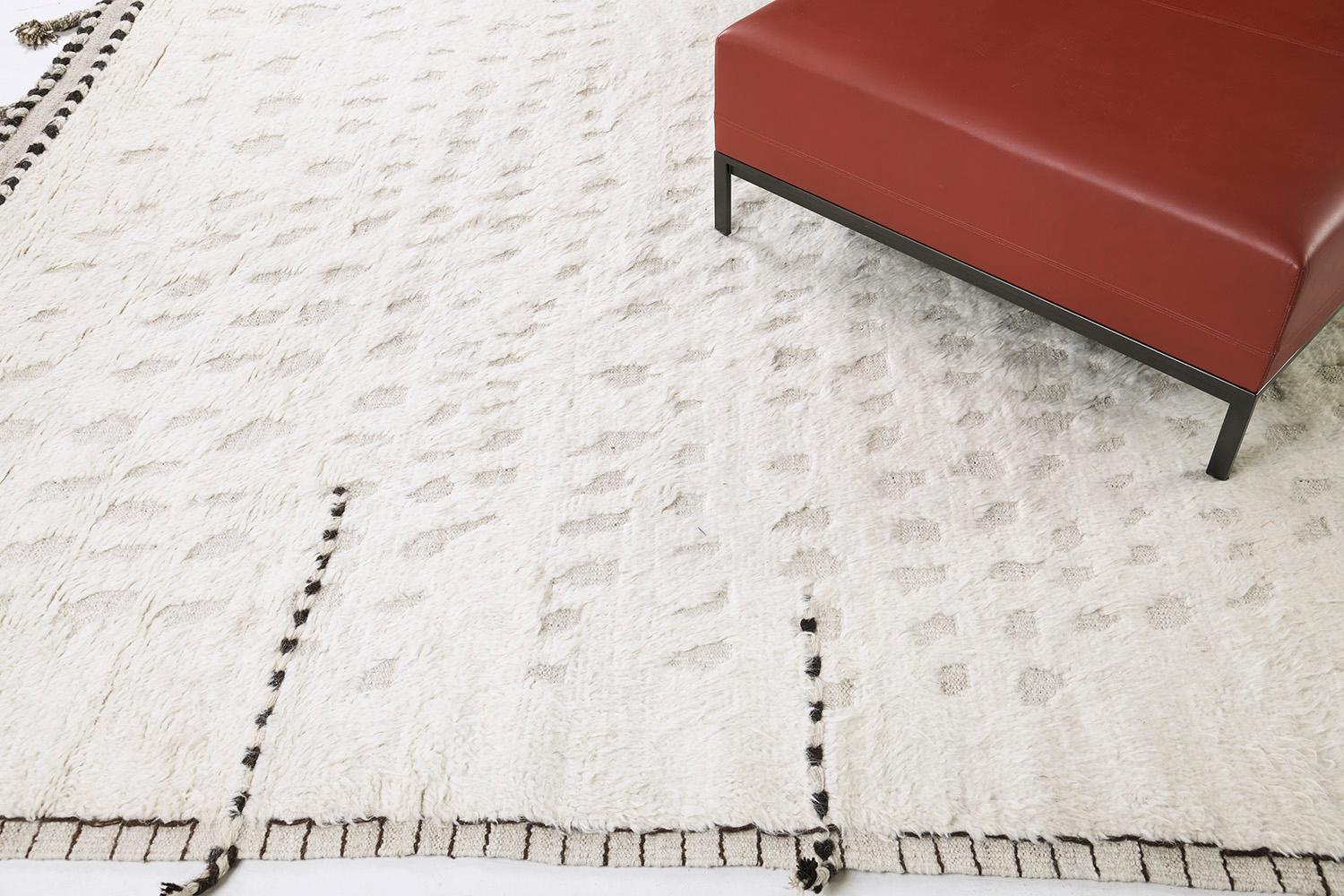 Olea' is a hand-knotted wool shag rug built on a flat-weave base. Tassel detailing run along the sides with dark stitch marks. This playful piece has a perfectly white foundation with round embossed details filling in the space and playing with the