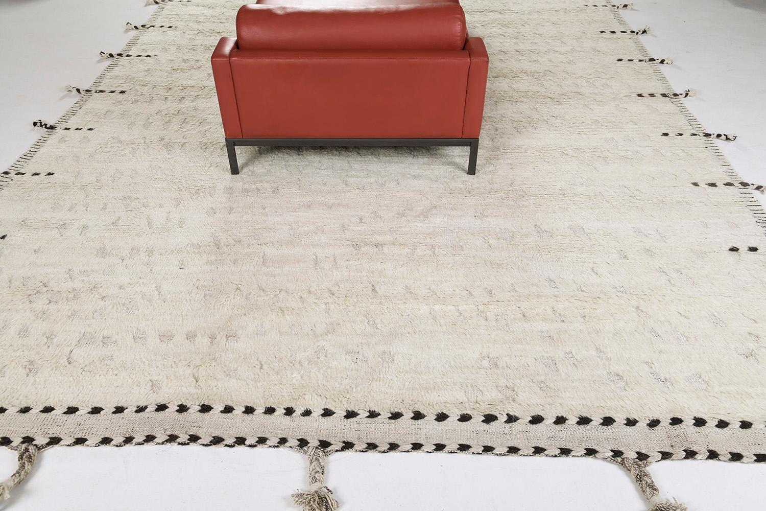 Olea est un tapis en laine noué à la main, construit sur une base à tissage plat. Les détails des pompons courent le long des côtés avec des marques de points foncés. Cette pièce ludique a une base parfaitement blanche avec des détails ronds en