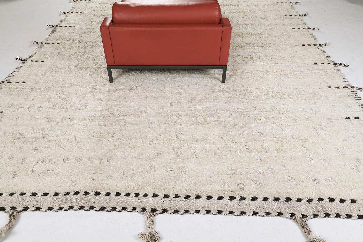 Olea is a hand-knotted wool rug built on a flat-weave base. Tassel detailing run along the sides with dark stitch marks. This playful piece has a perfectly white foundation with round embossed details filling in the space and playing with the depth