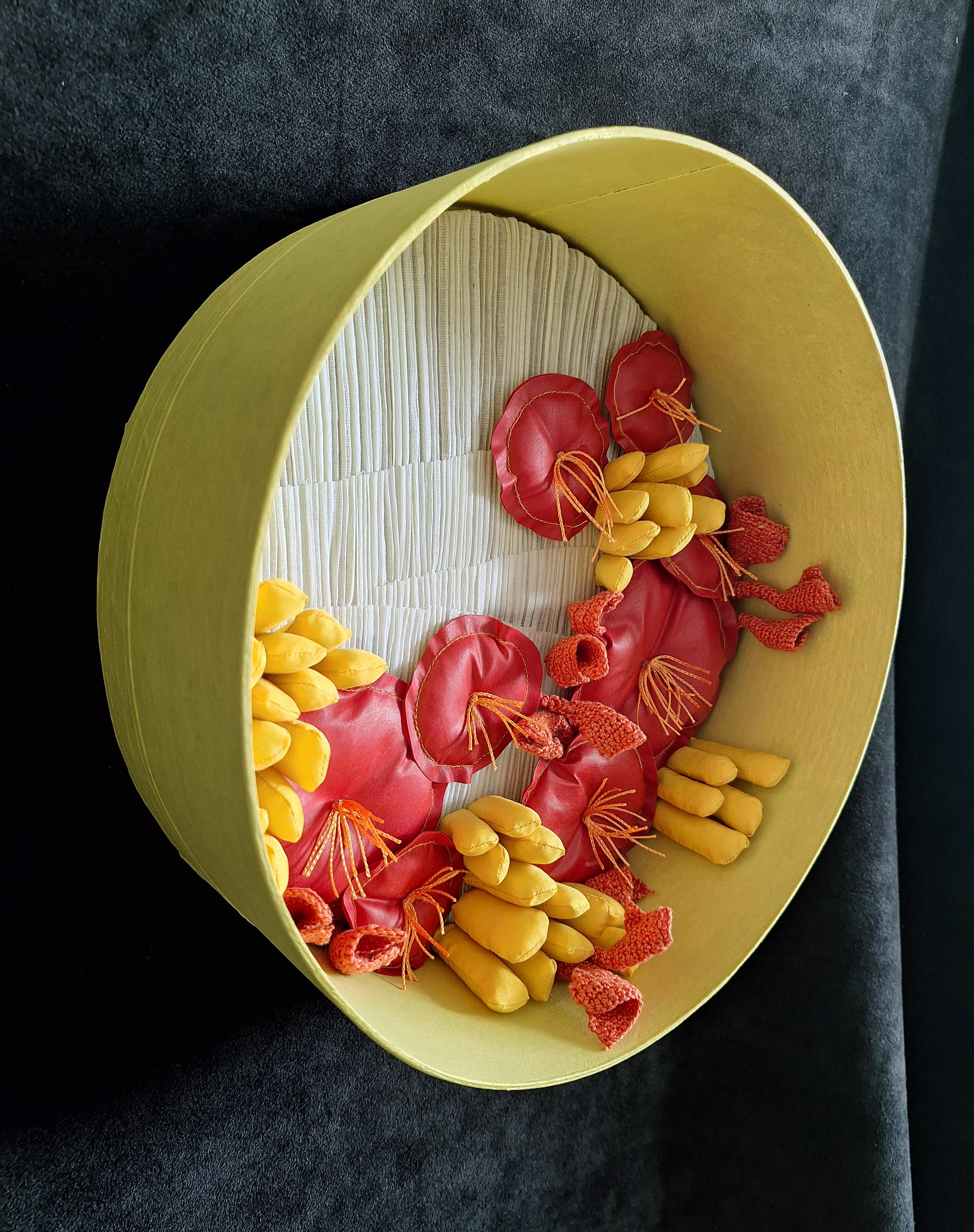 En Jardín de verano, Olga Radionova presenta una asombrosa metáfora visual de la abundancia y la calidez. Mediante vainas de color amarillo brillante, flores de color rojo intenso y suaves capas escultóricas, la pieza se convierte en un portal a la