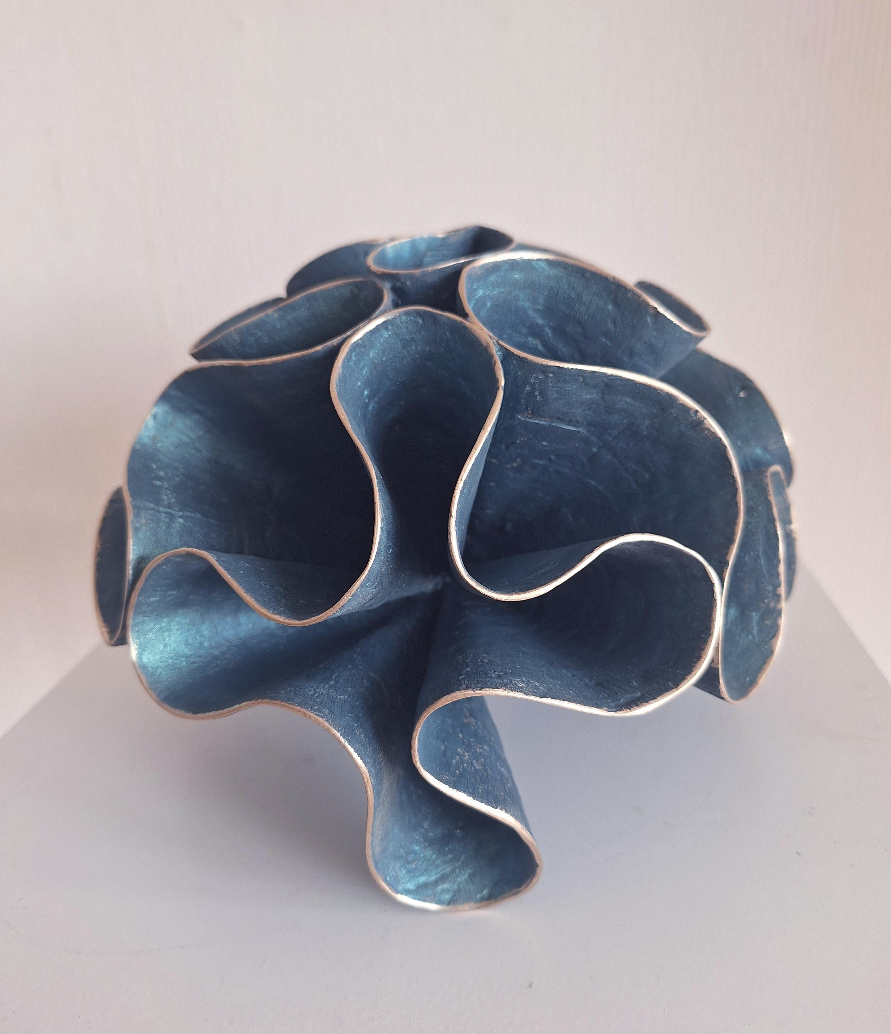In Coral Mood, bronze transforms into a living organism. The organic form recalls underwater reefs, echoing the fragile yet eternal architecture of the sea. Its folds and curves suggest the rhythm of the ocean’s breath, while the turquoise-green