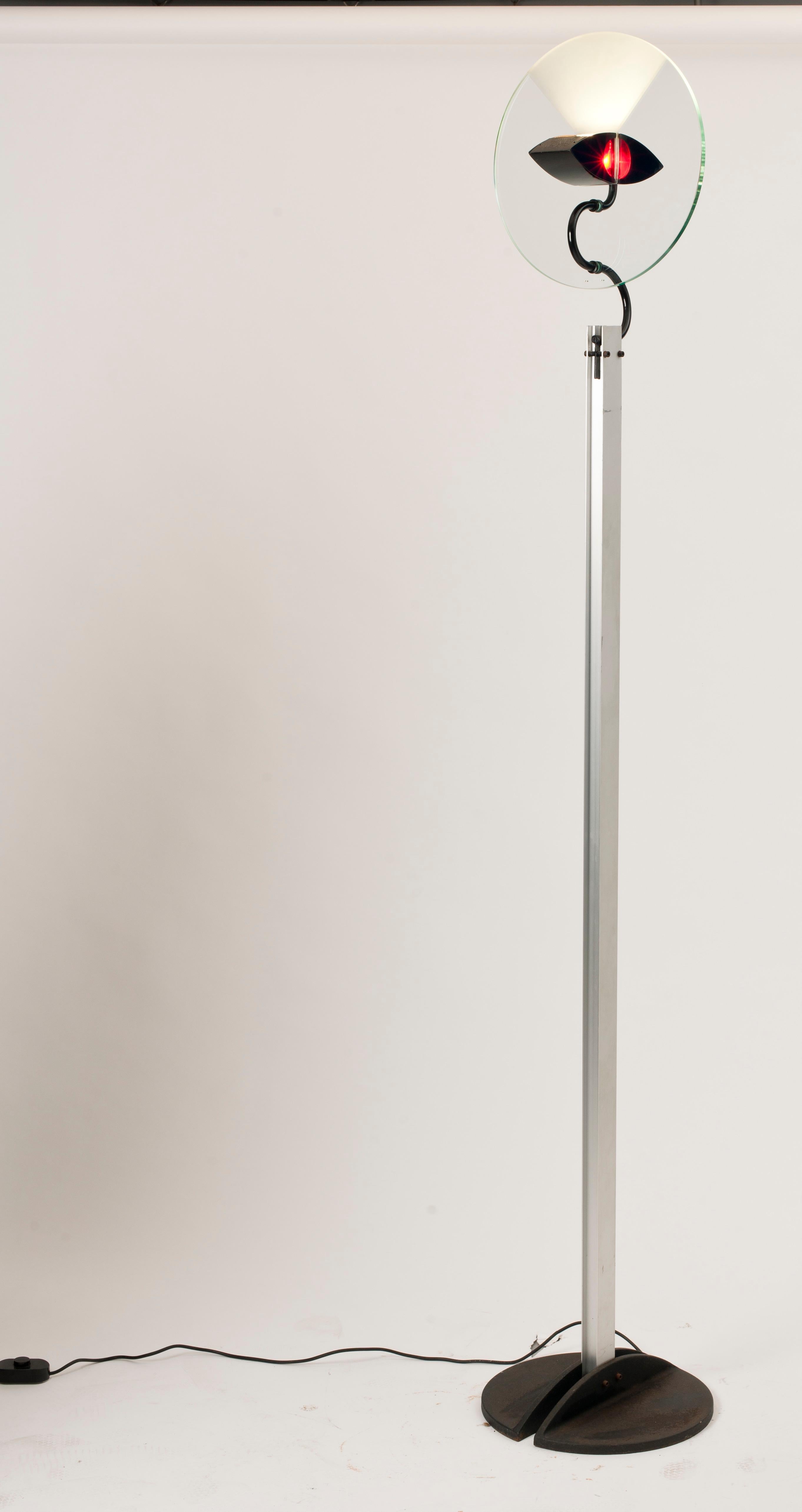 Olimpia floor lamp by Carlo Forcolini for Artemide. Eye-shaped lamp within a glass disc on an aluminium support and cast iron circular base.

Born in Como in 1947, Carlo Forcolini graduated with a diploma in Fine Art at the Brera Accademy in